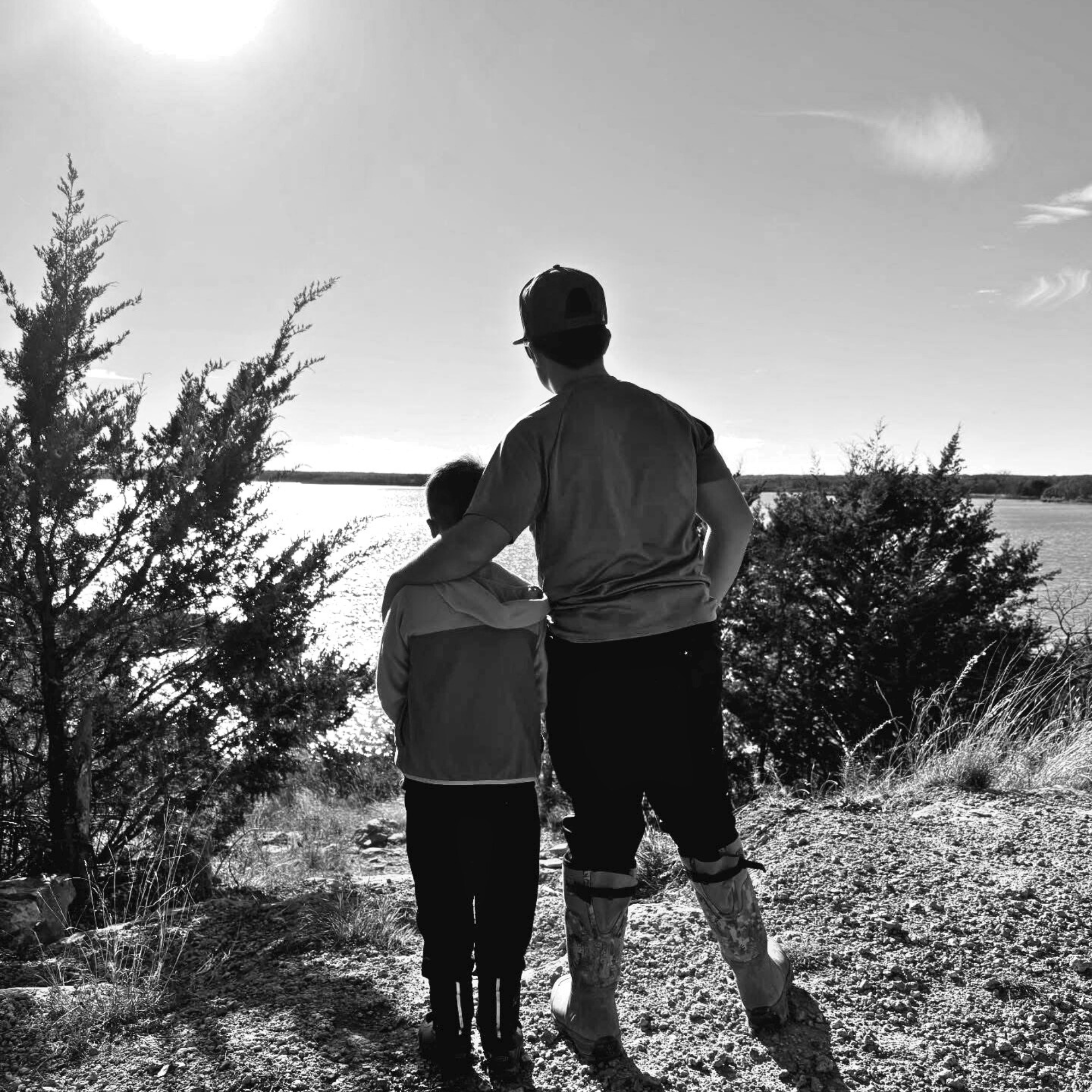 Two people standing together on a trail looking out over a scenic landscape.