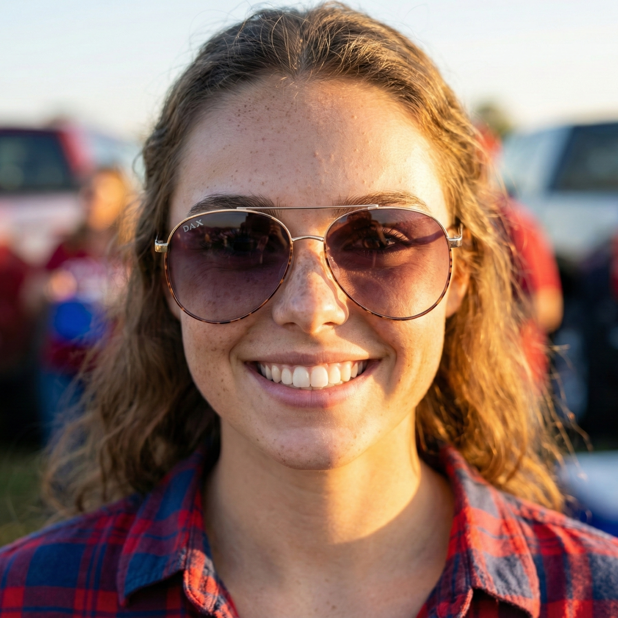 Woman wearing sunglasses and a plaid shirt with a blurred background