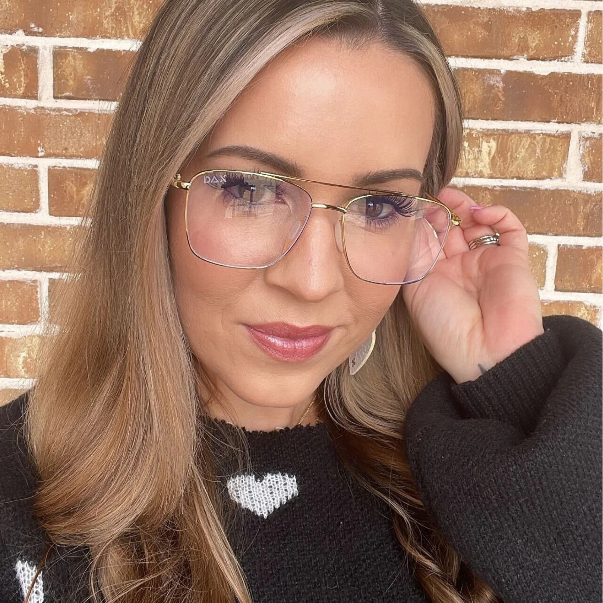 Woman wearing glasses with a brick wall background