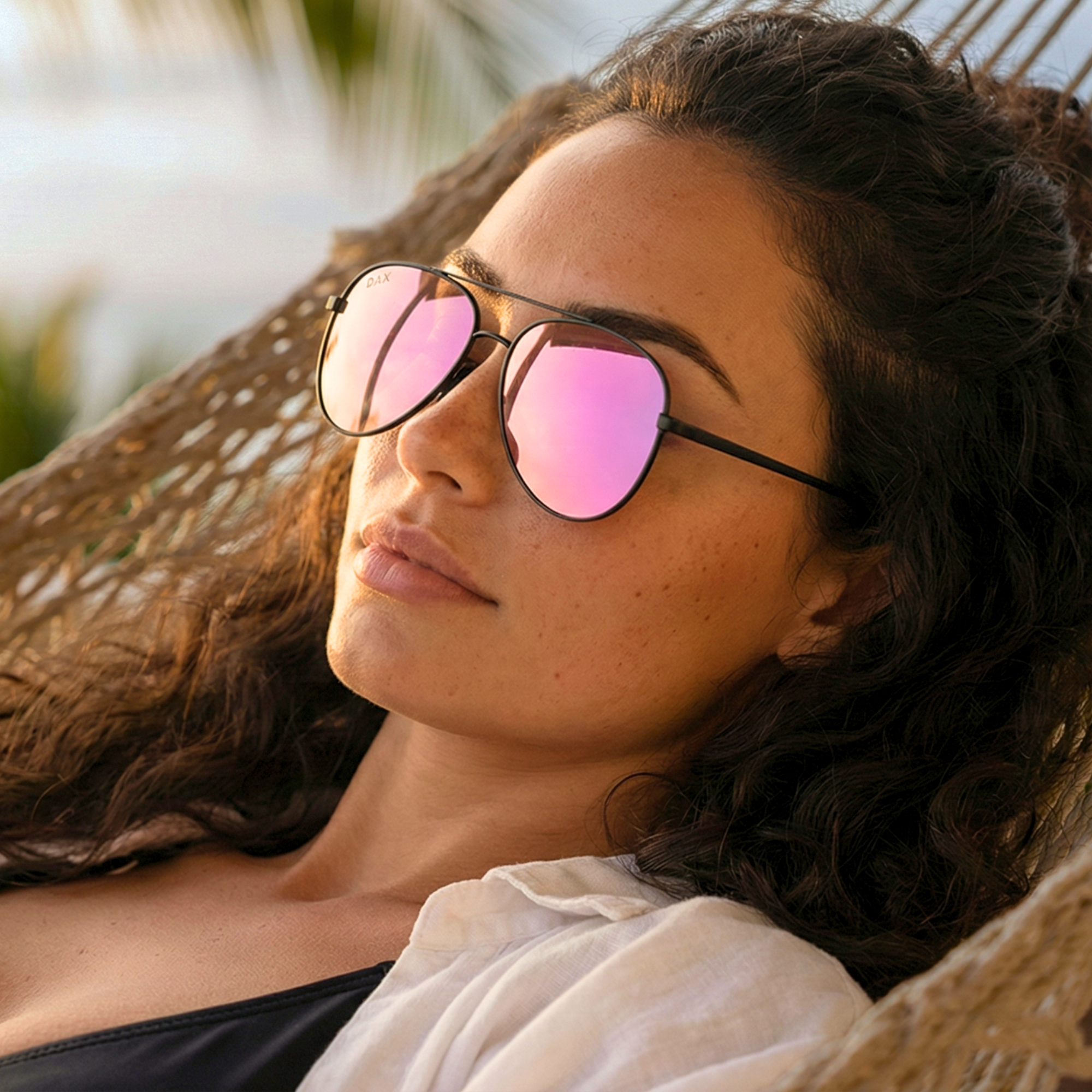 Woman wearing pink-tinted sunglasses in a natural setting
