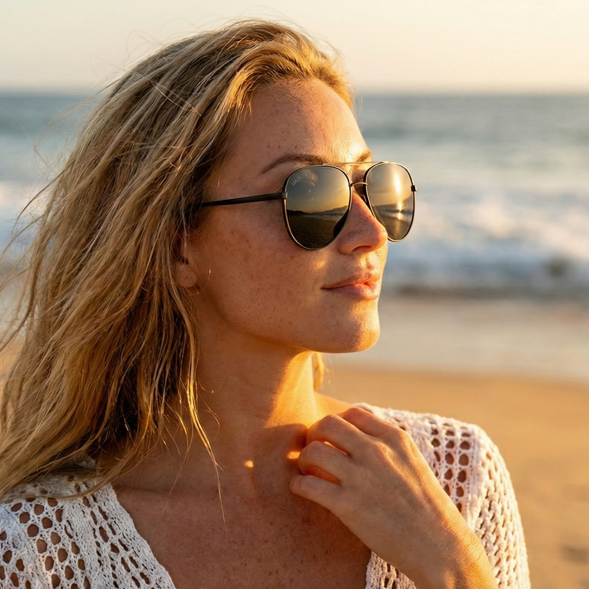 Woman wearing sunglasses on a beach at sunset