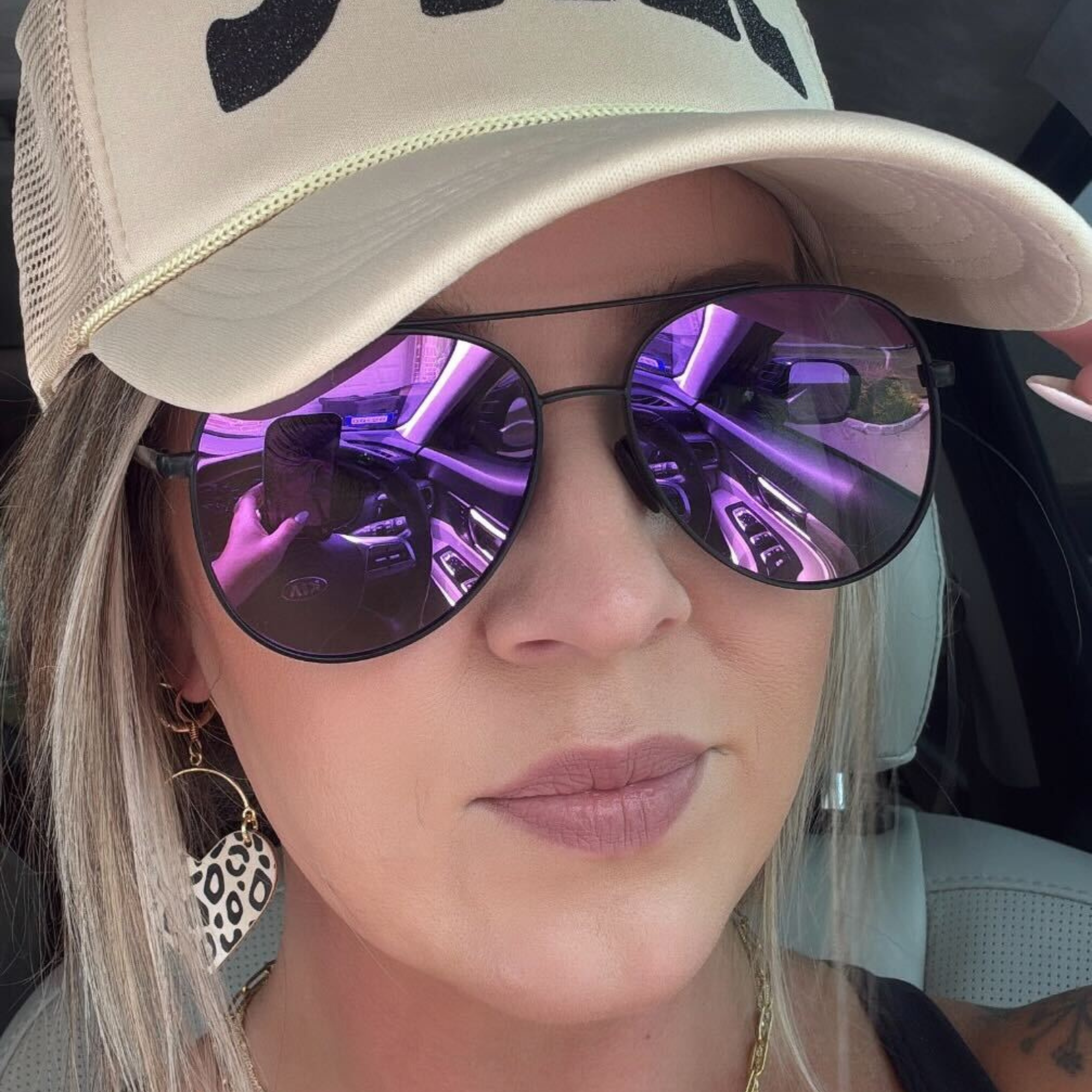 Person wearing a beige cap and purple sunglasses with car interior reflection
