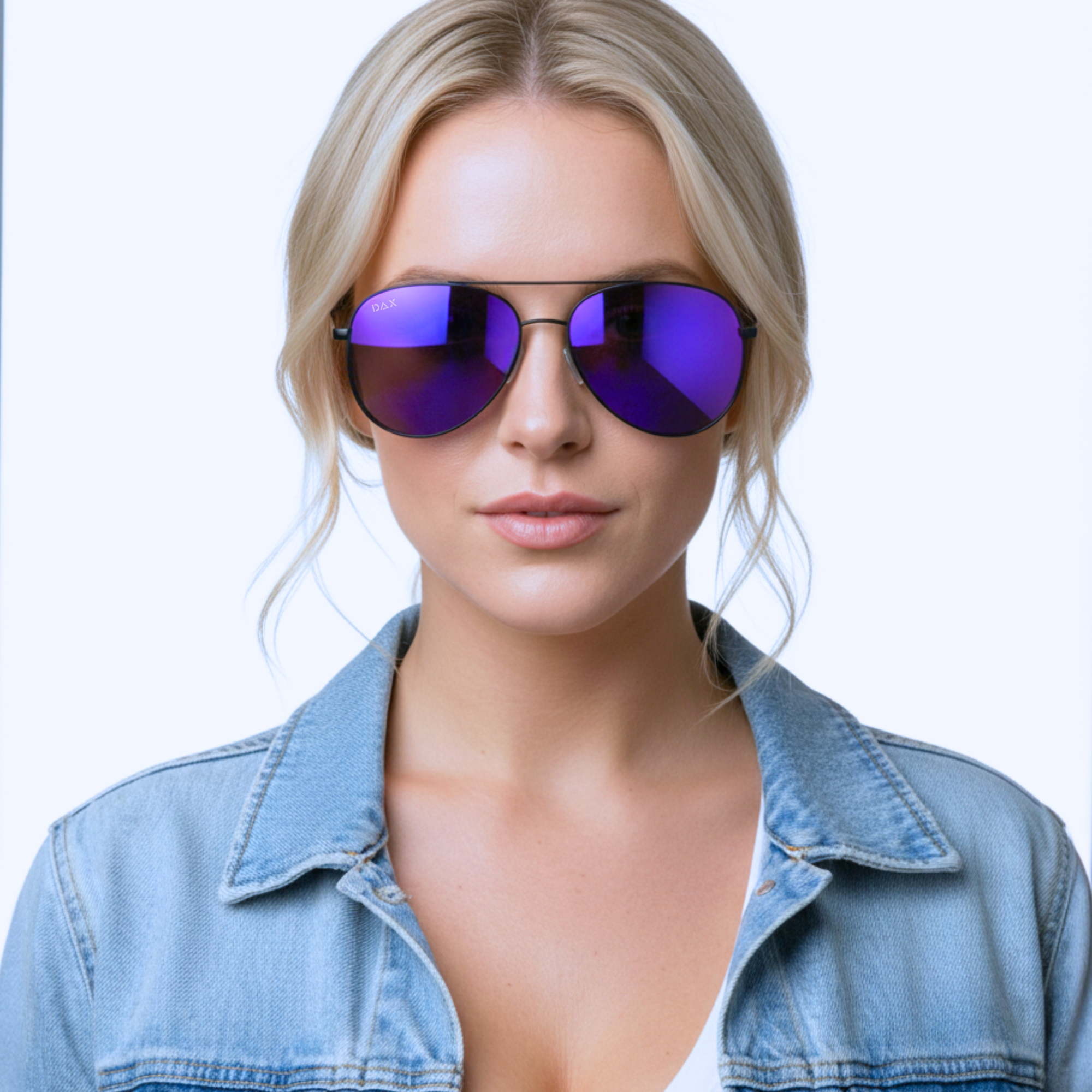 Woman wearing purple reflective sunglasses and a denim jacket on a light blue background