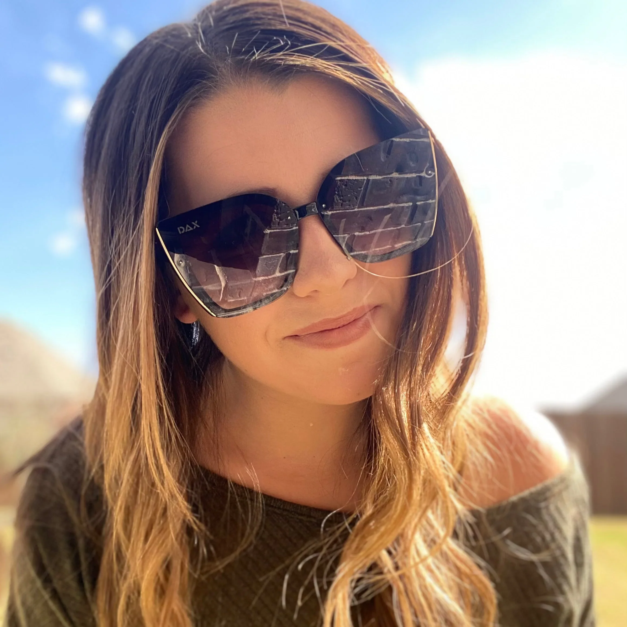Woman wearing large sunglasses with a blurred natural background