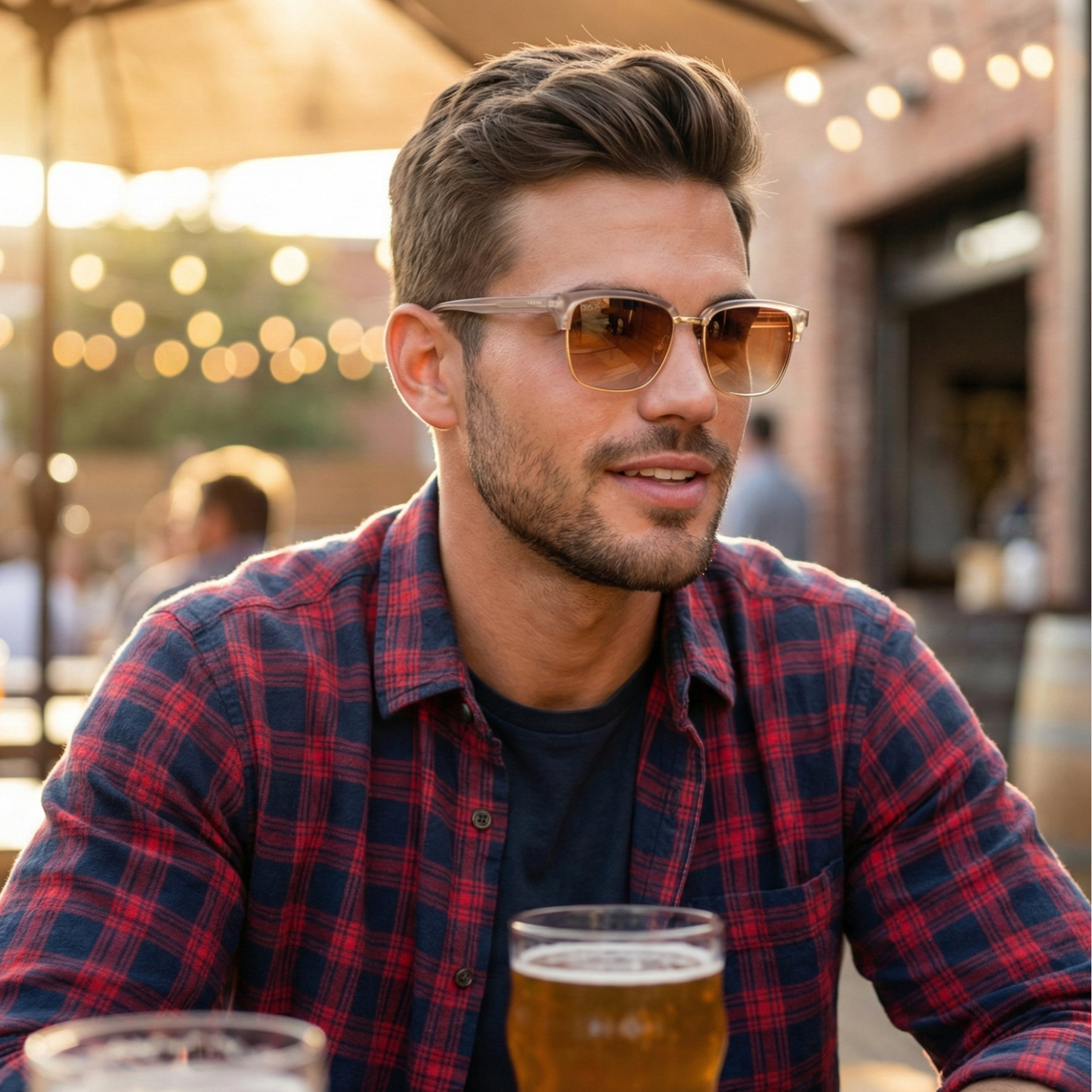 Man wearing sunglasses and a plaid shirt with a beer glass outdoors