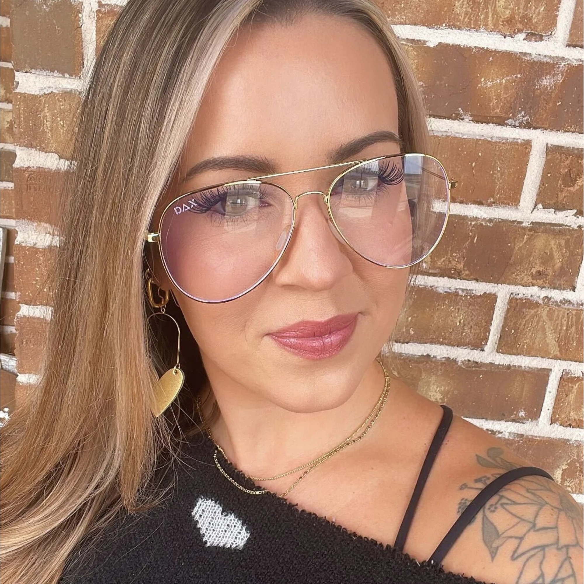 Woman wearing glasses with a brick wall background