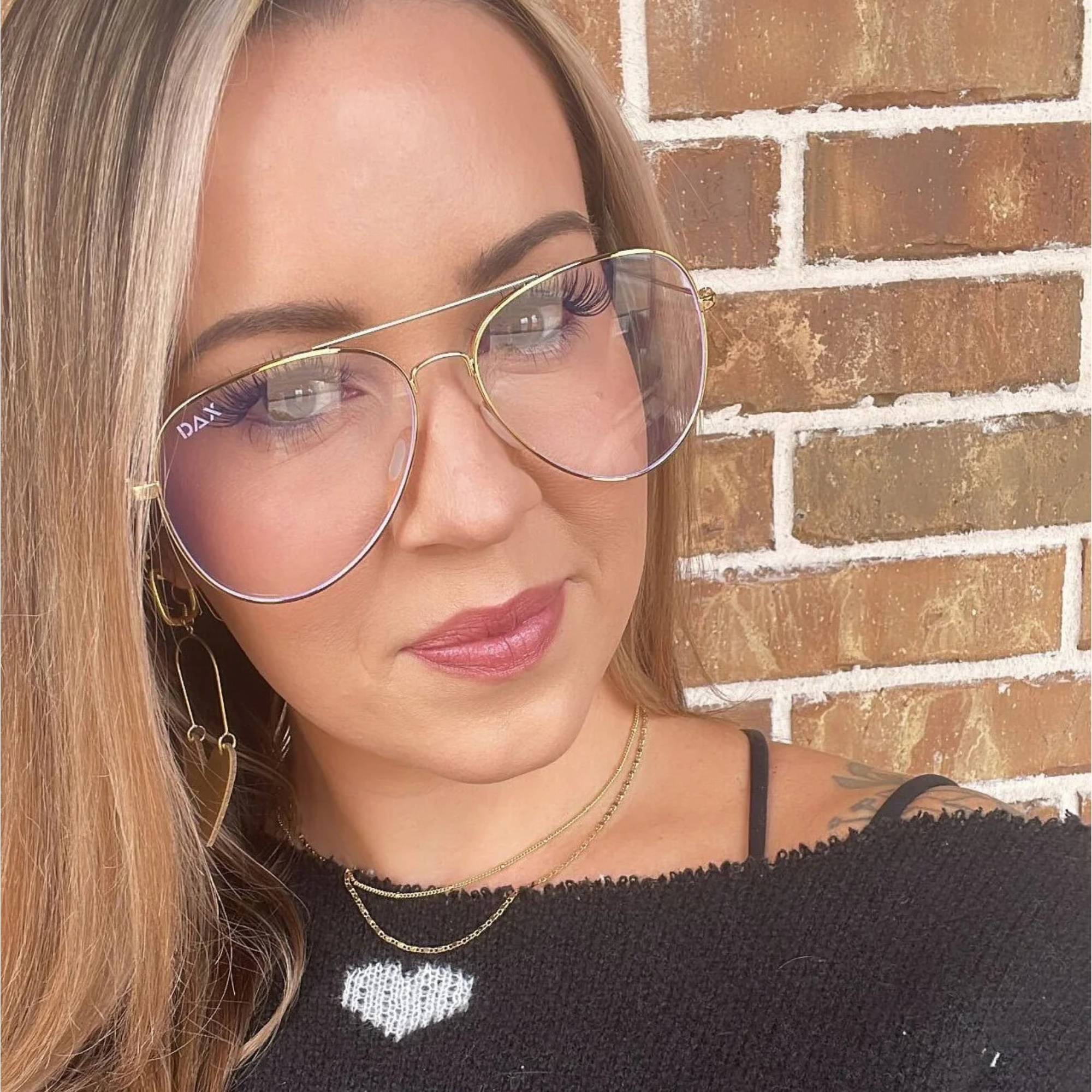 Woman wearing large sunglasses with a brick wall background