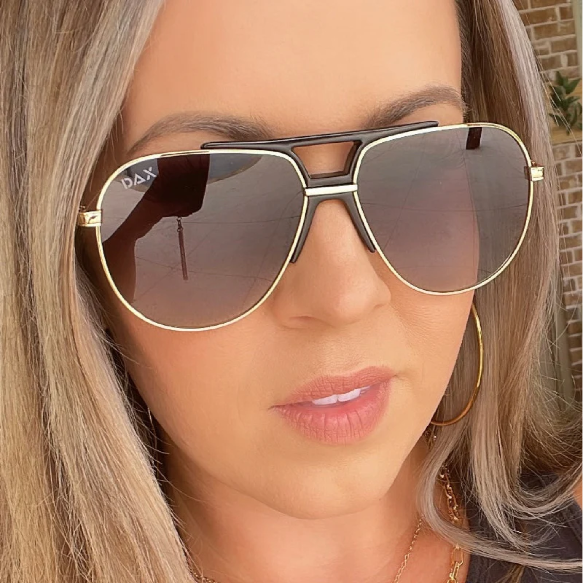 Close-up of a person wearing DAX sunglasses with a neutral background