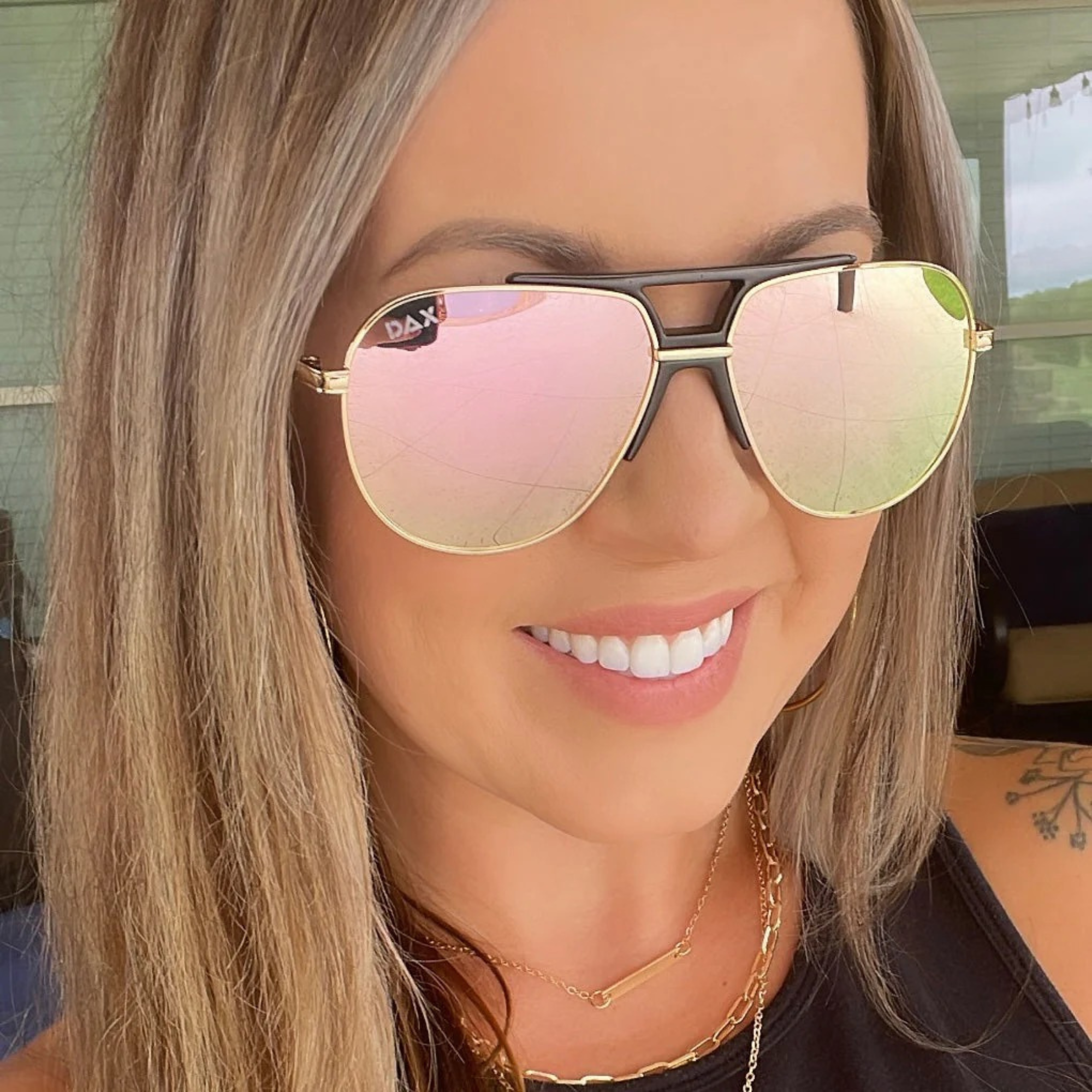 Person wearing pink-tinted sunglasses with a blurred background