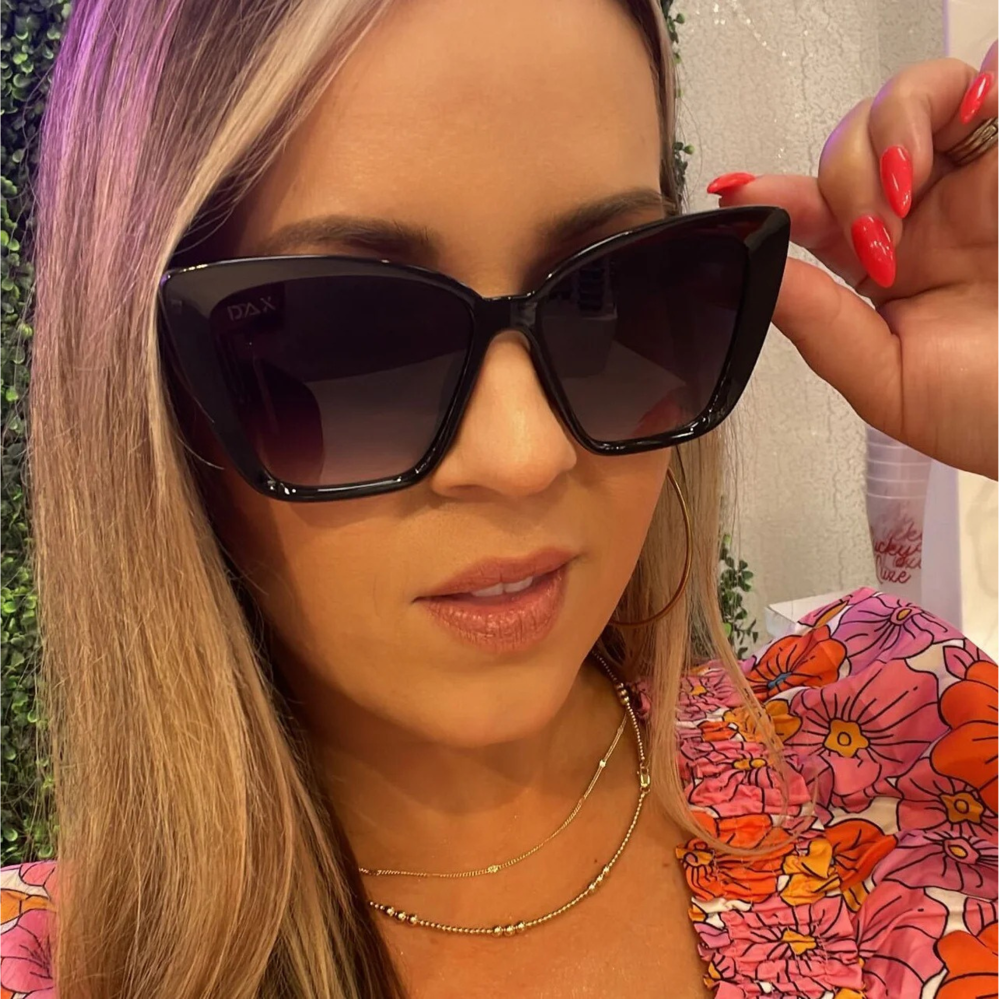 Woman wearing large black sunglasses with a blurred background