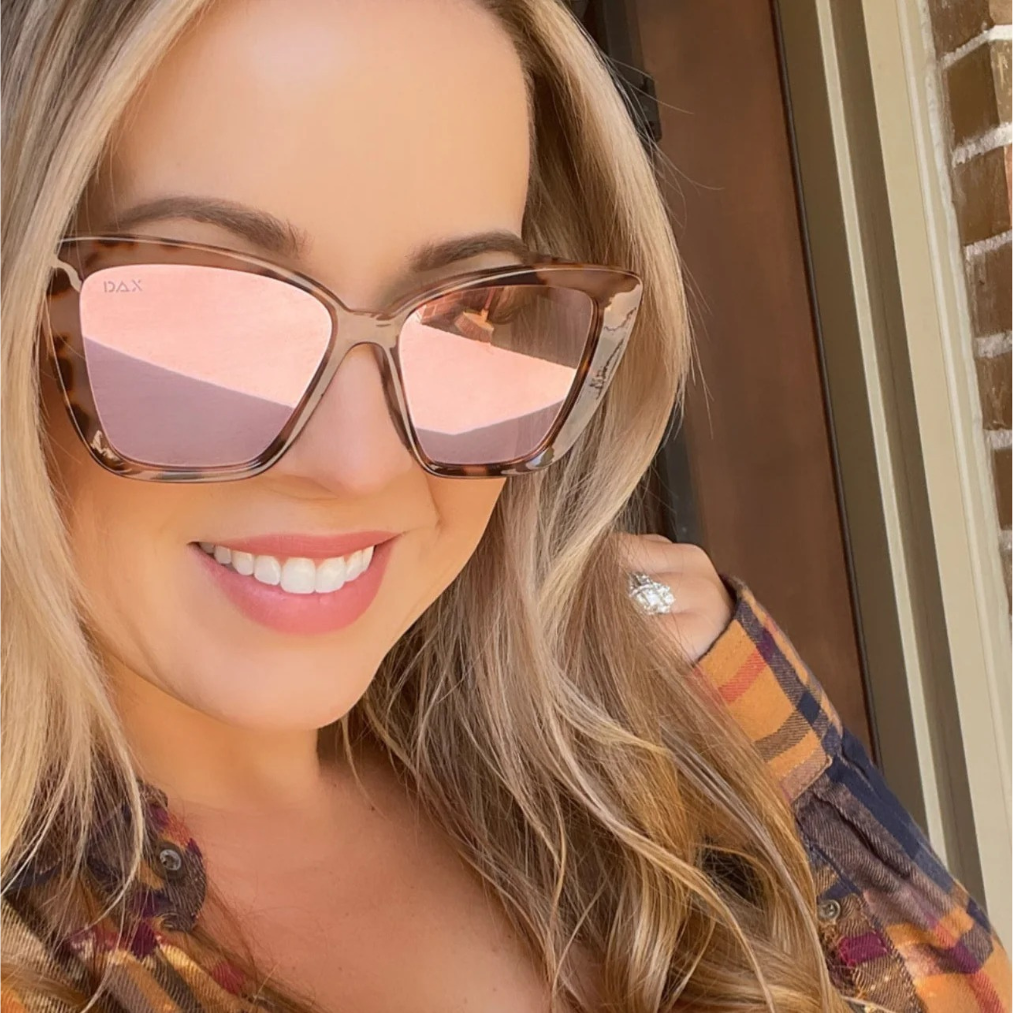 Woman wearing sunglasses with a plaid jacket indoors
