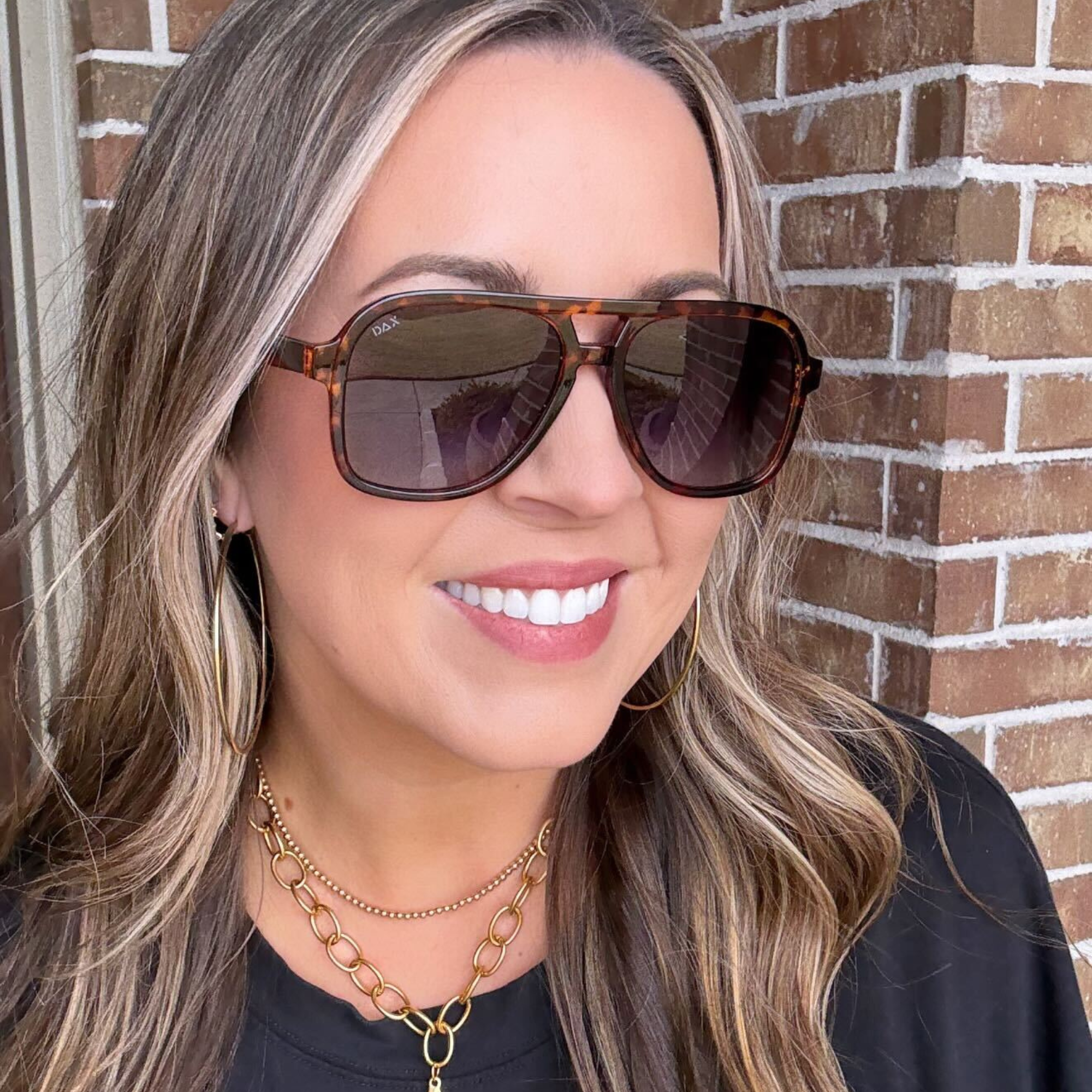 Woman wearing sunglasses with a brick wall background