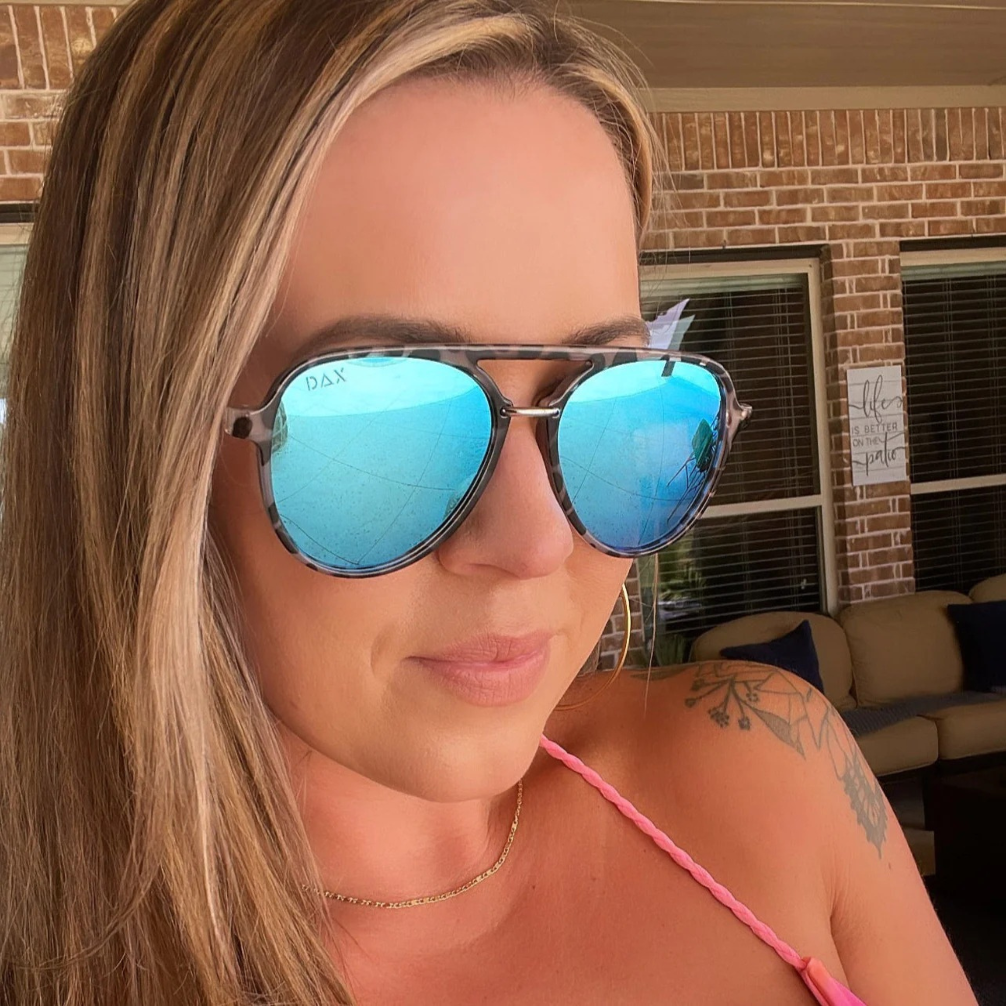 Woman wearing blue reflective sunglasses with a blurred background