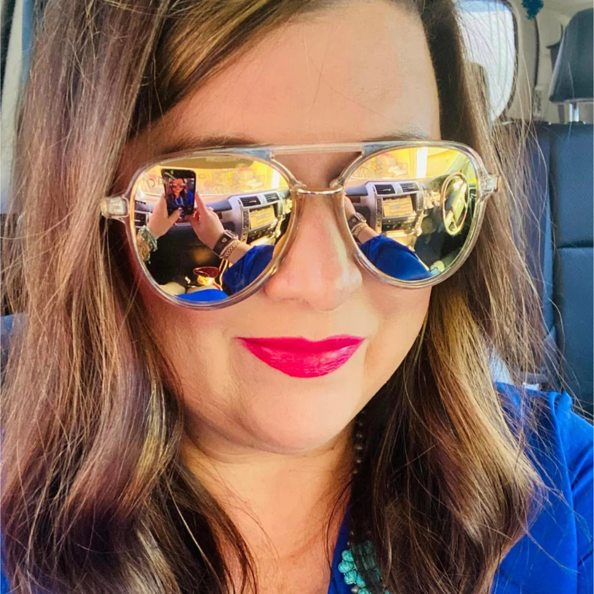 Woman wearing gold reflective sunglasses with a blurred background