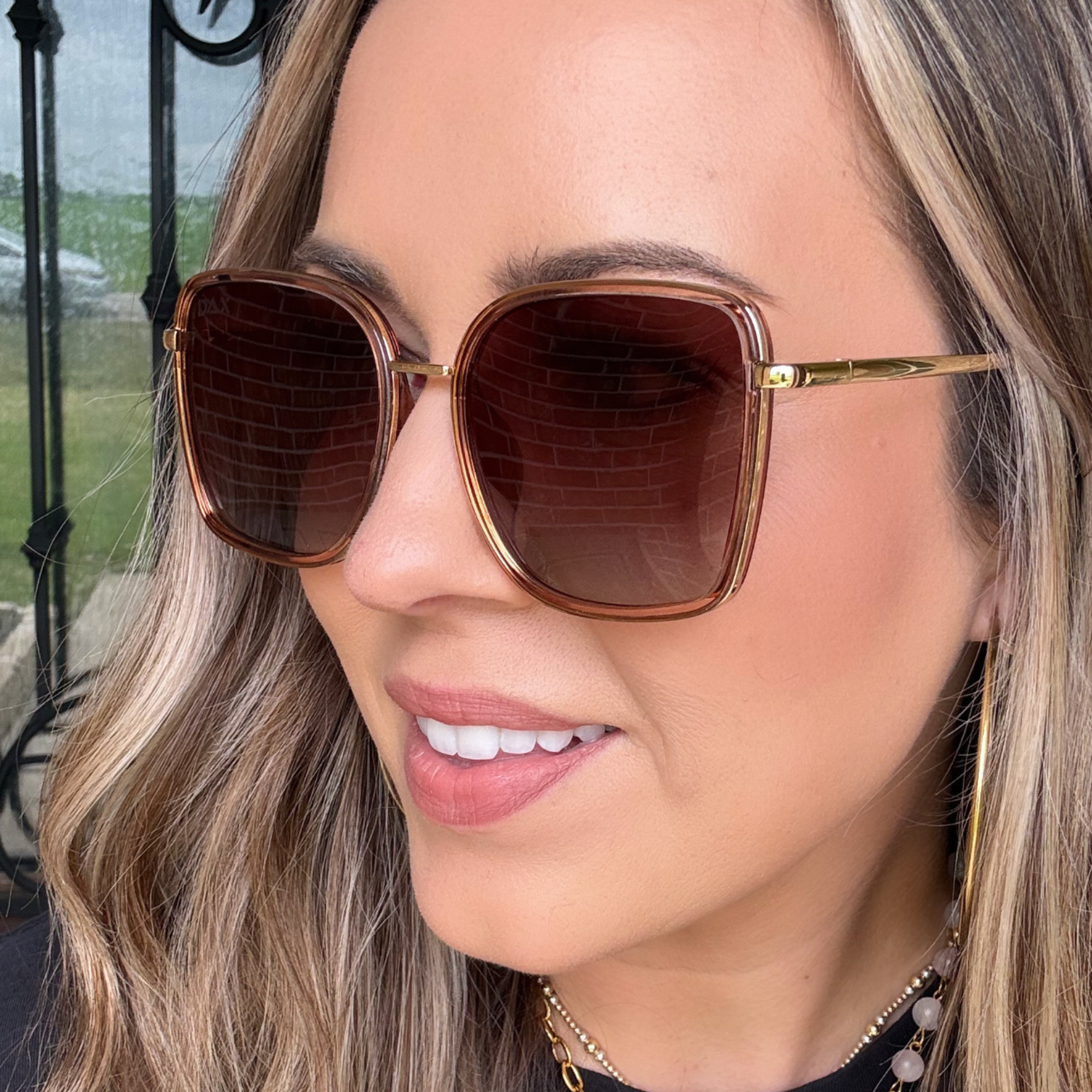 Close-up of a person wearing brown sunglasses with a blurred background