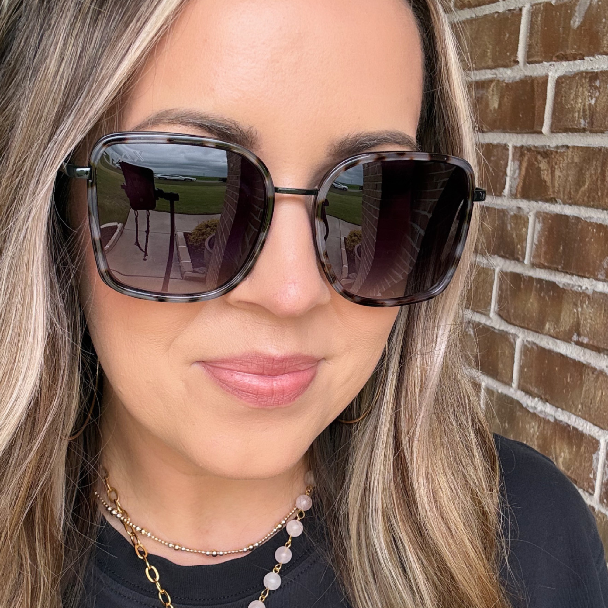 Woman wearing sunglasses with a brick wall background