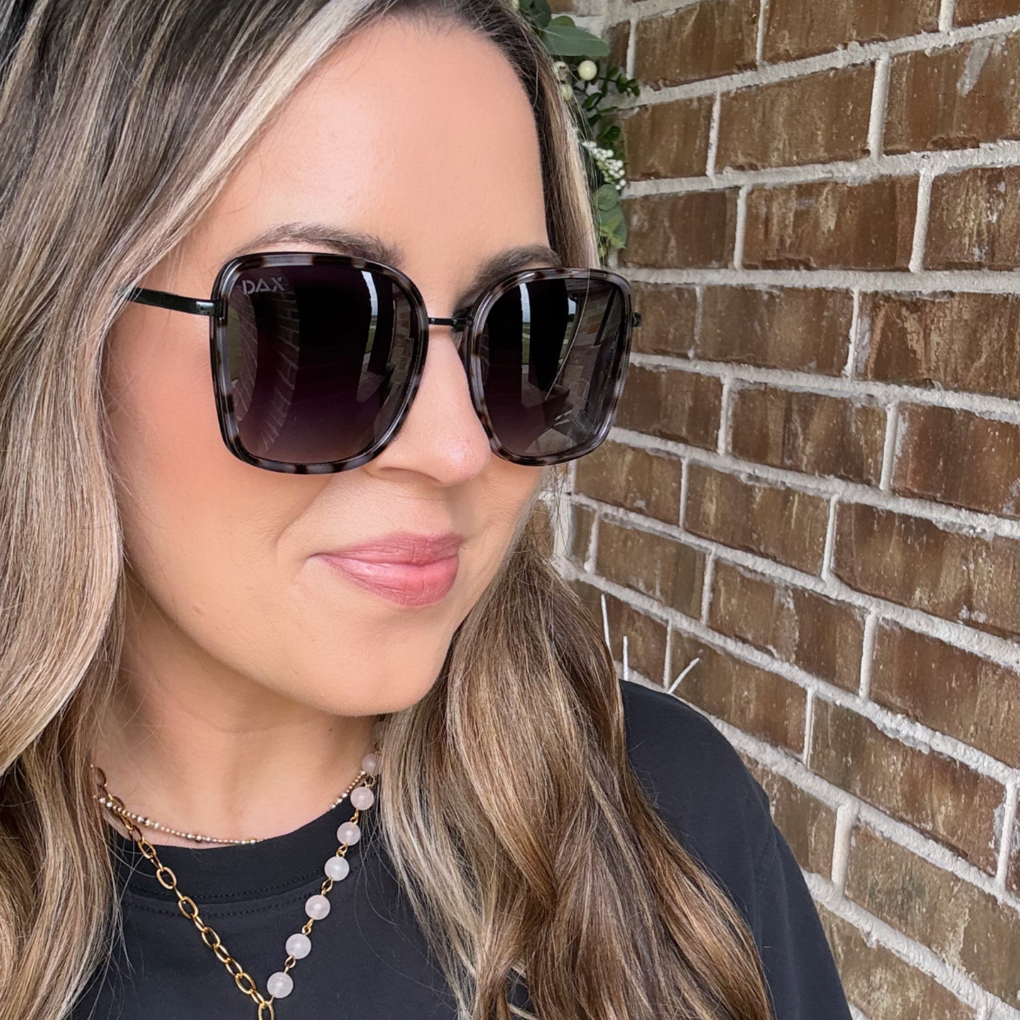 Woman wearing sunglasses with a brick wall background