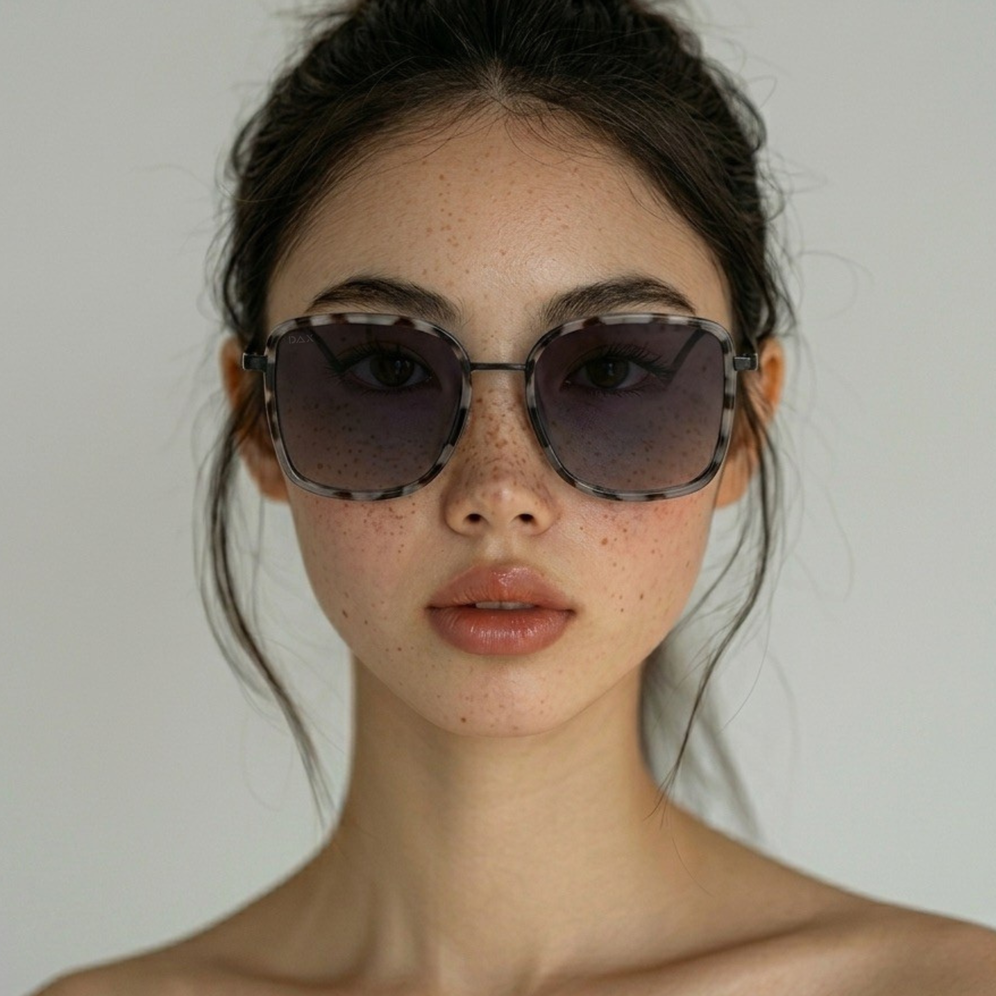 Woman wearing dark sunglasses against a neutral background