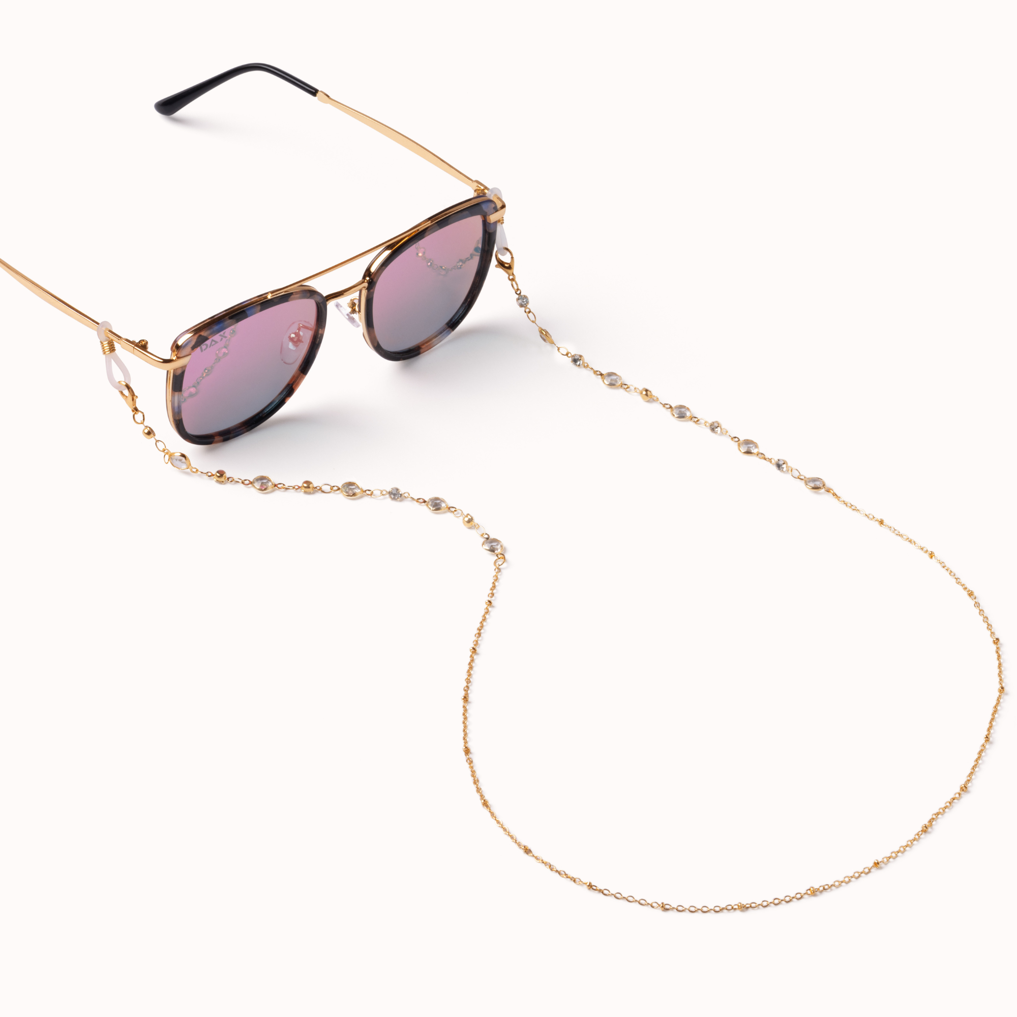 Gold-framed sunglasses with tortoiseshell-patterned lenses and a matching gold chain strap, displayed on a clean off-white background.