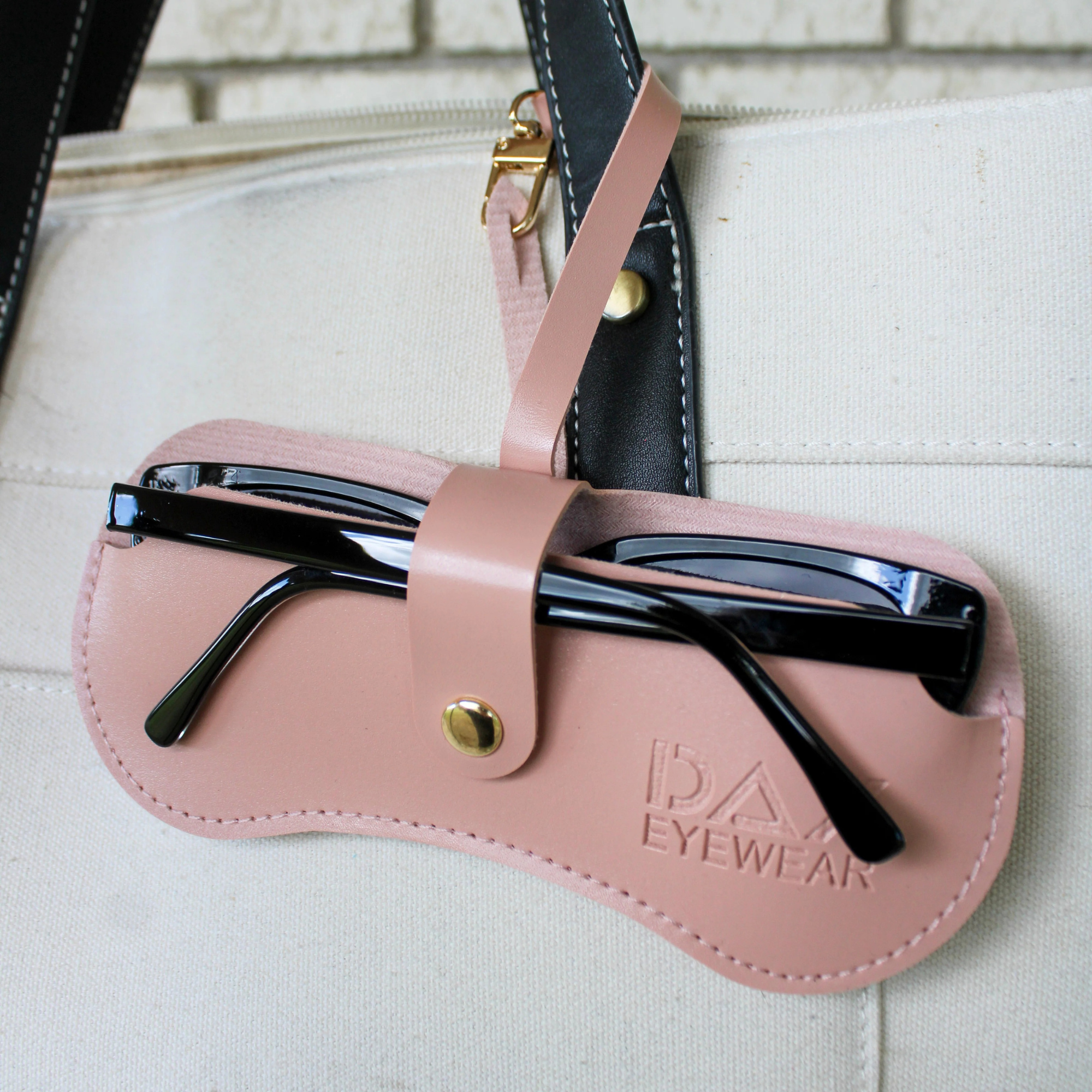 Pink sunglasses case with black sunglasses on a white surface, featuring the brand 'DAX'.