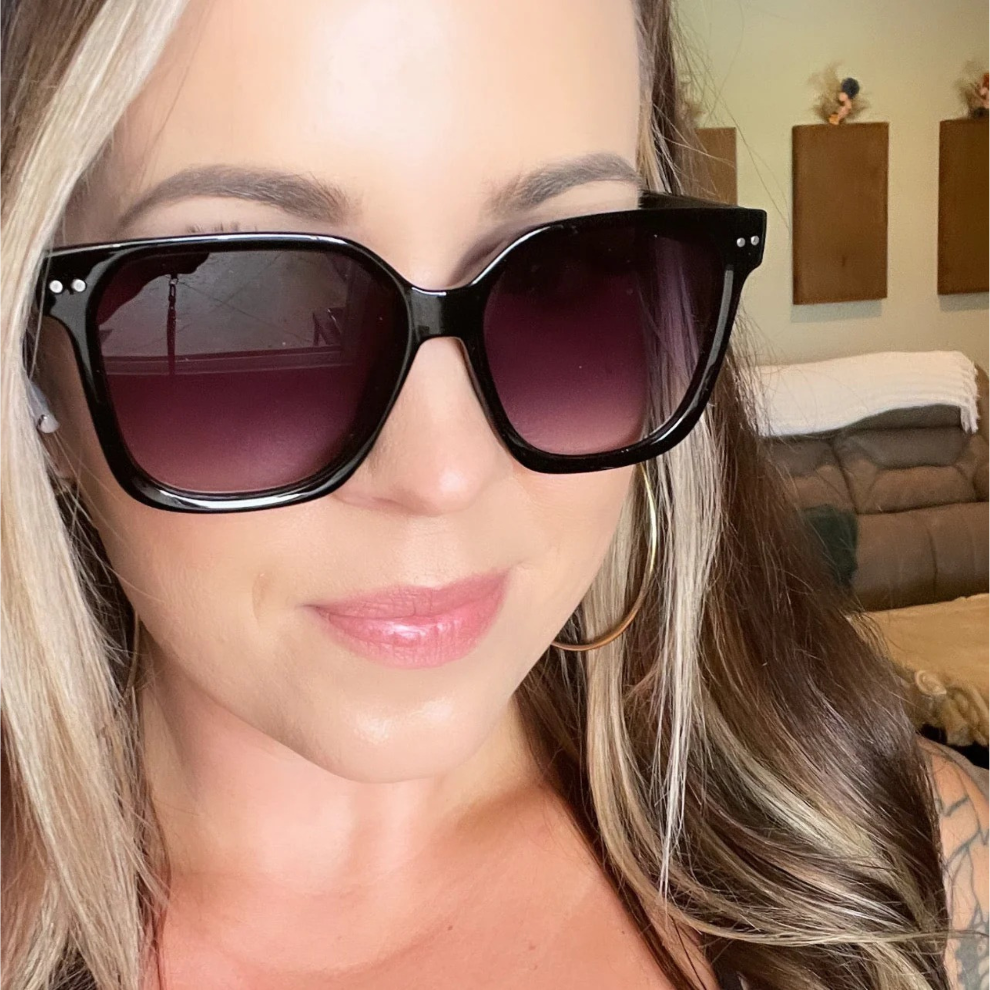 Woman wearing black sunglasses with a blurred indoor background