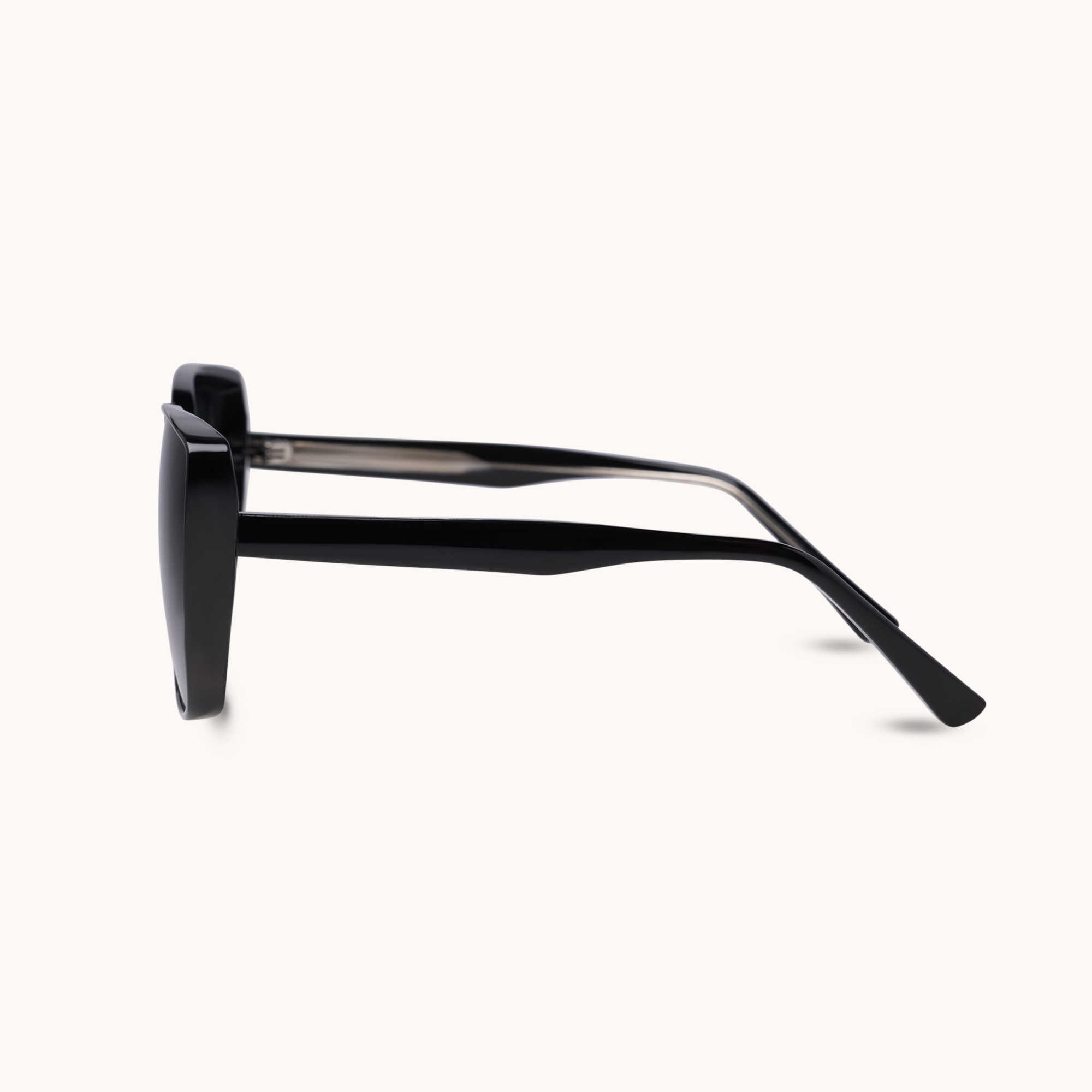 A pair of square-frame sunglasses with thick black acetate frames and translucent dark gray temples, shown in profile against a light cream background.
