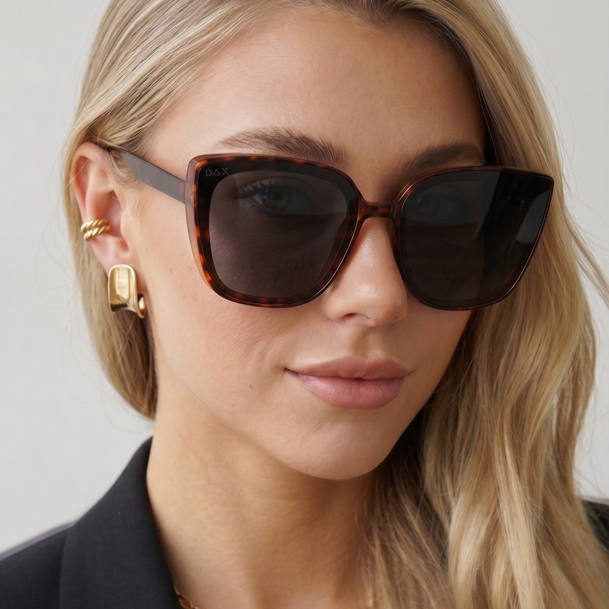 Woman wearing tortoiseshell sunglasses with a neutral background