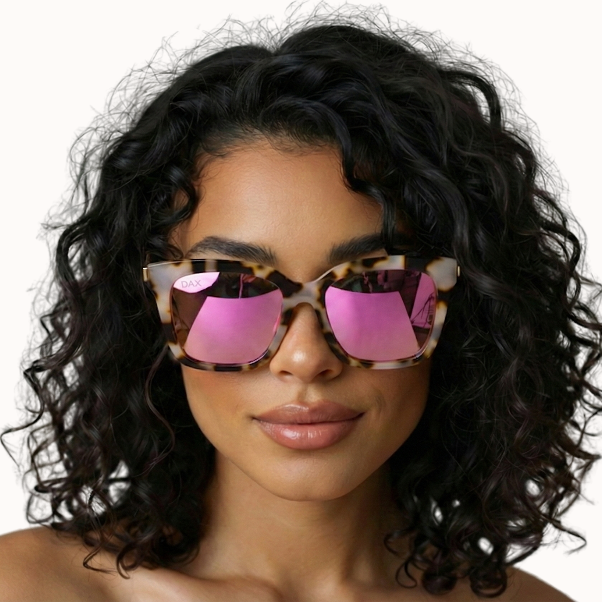 Woman wearing sunglasses with pink lenses and a tortoiseshell frame on a white background