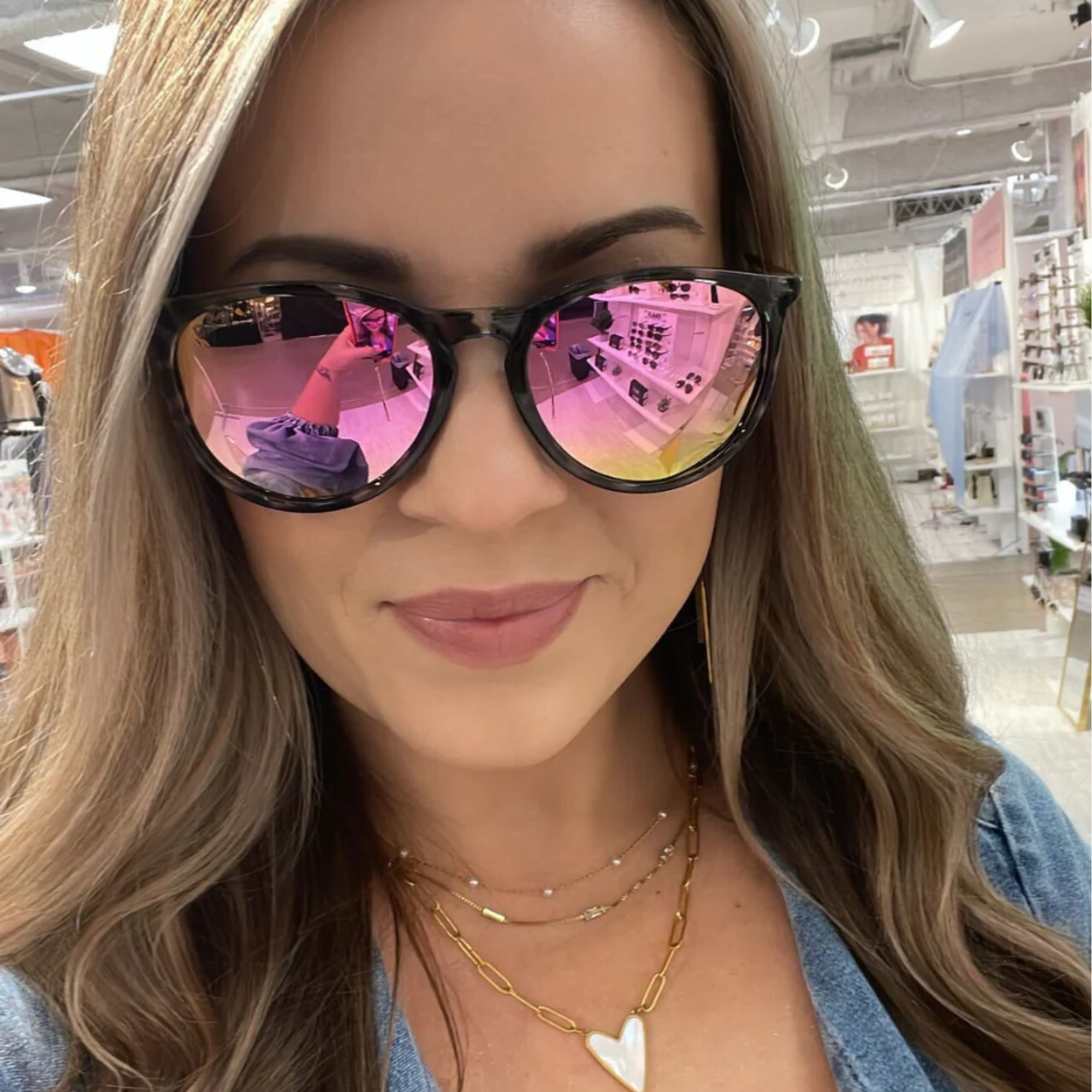 Woman wearing pink-tinted sunglasses in a store setting
