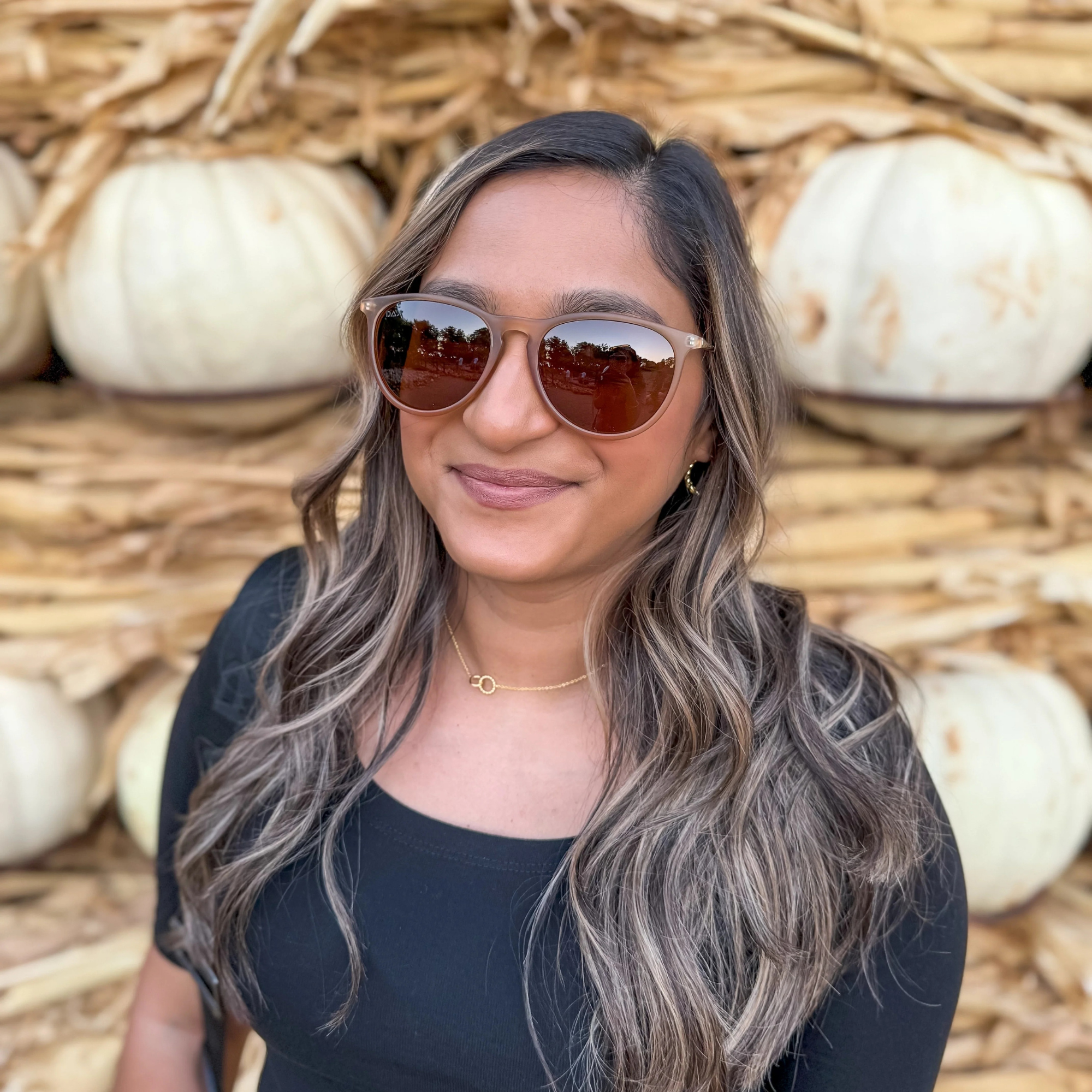 Woman wearing sunglasses with pumpkins in the background