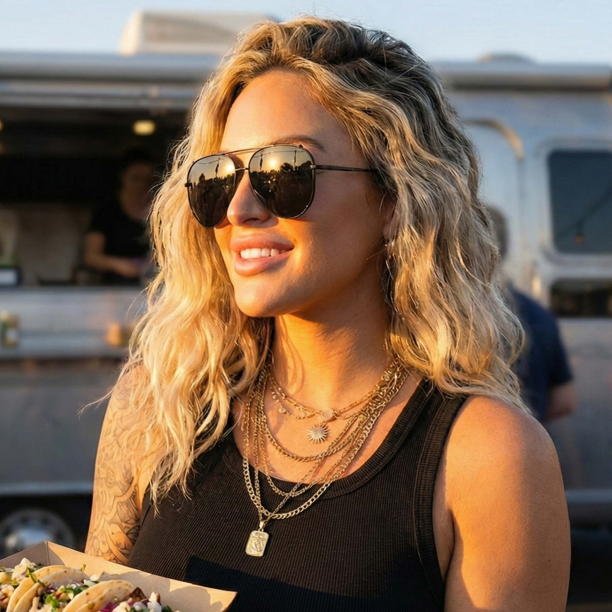 Woman wearing sunglasses with a food truck in the background