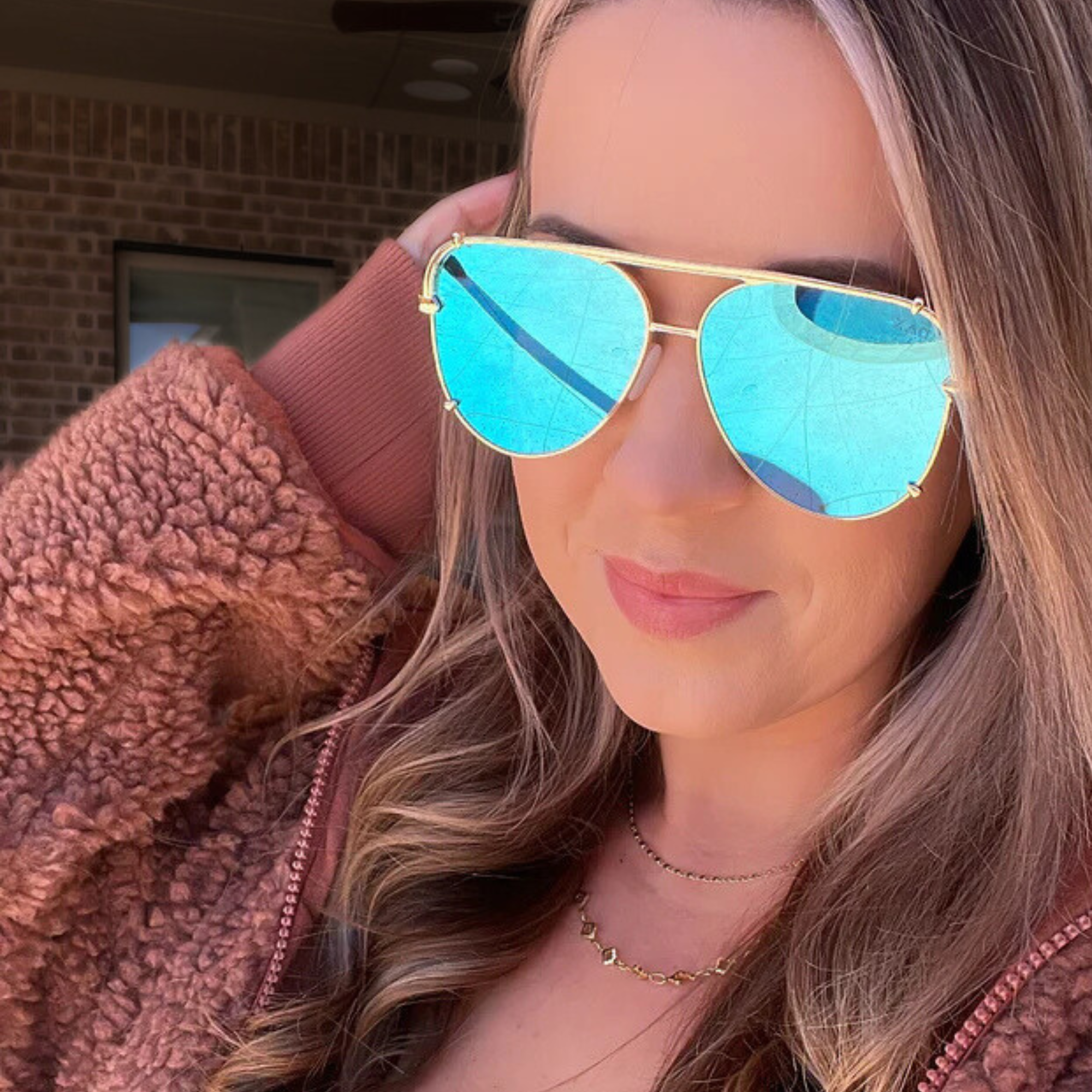 Woman wearing turquoise sunglasses with gold frame