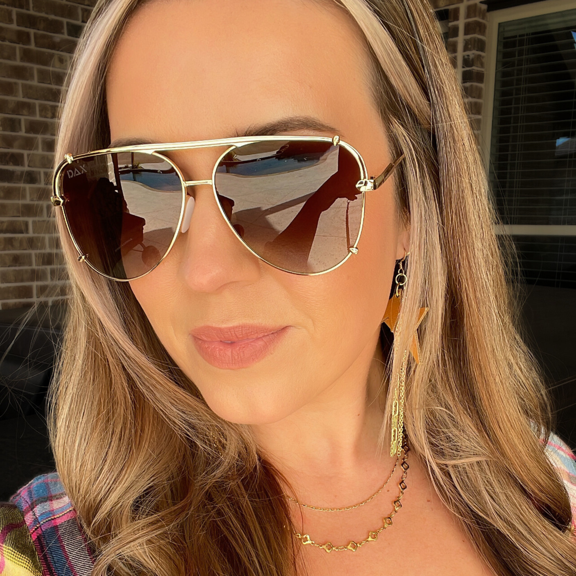 Woman wearing gold aviator sunglasses with a blurred background