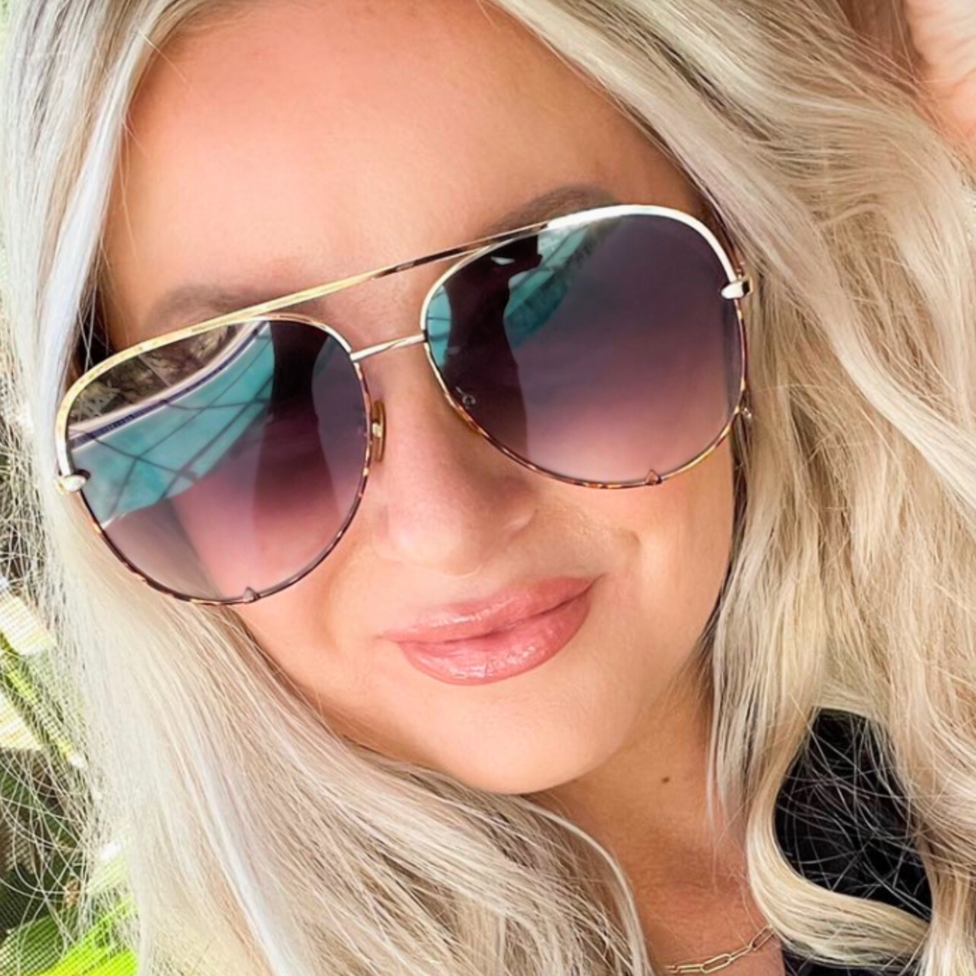 Close-up of a person wearing large sunglasses with a blurred background