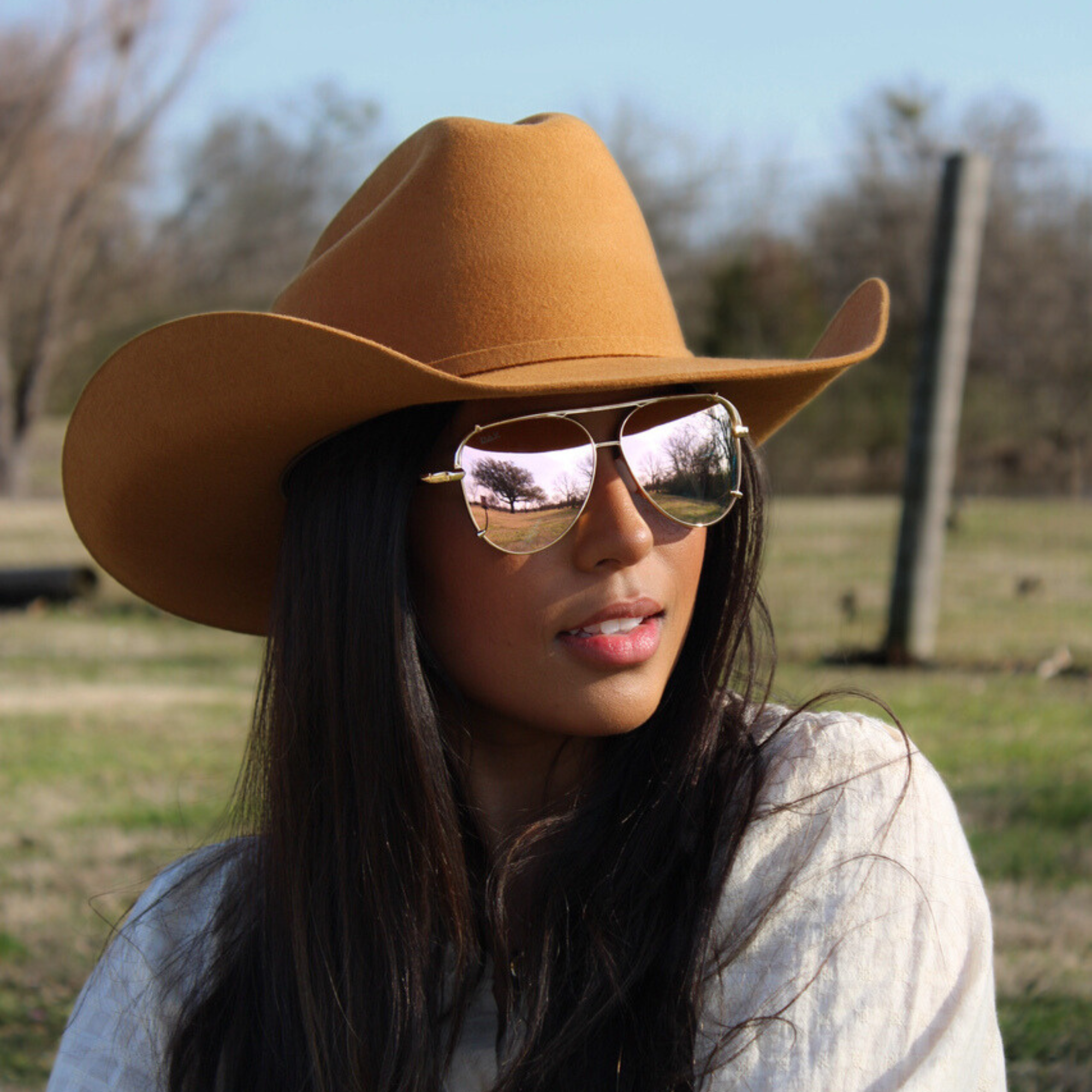 Woman wearing a brown cowboy hat and sunglasses outdoors