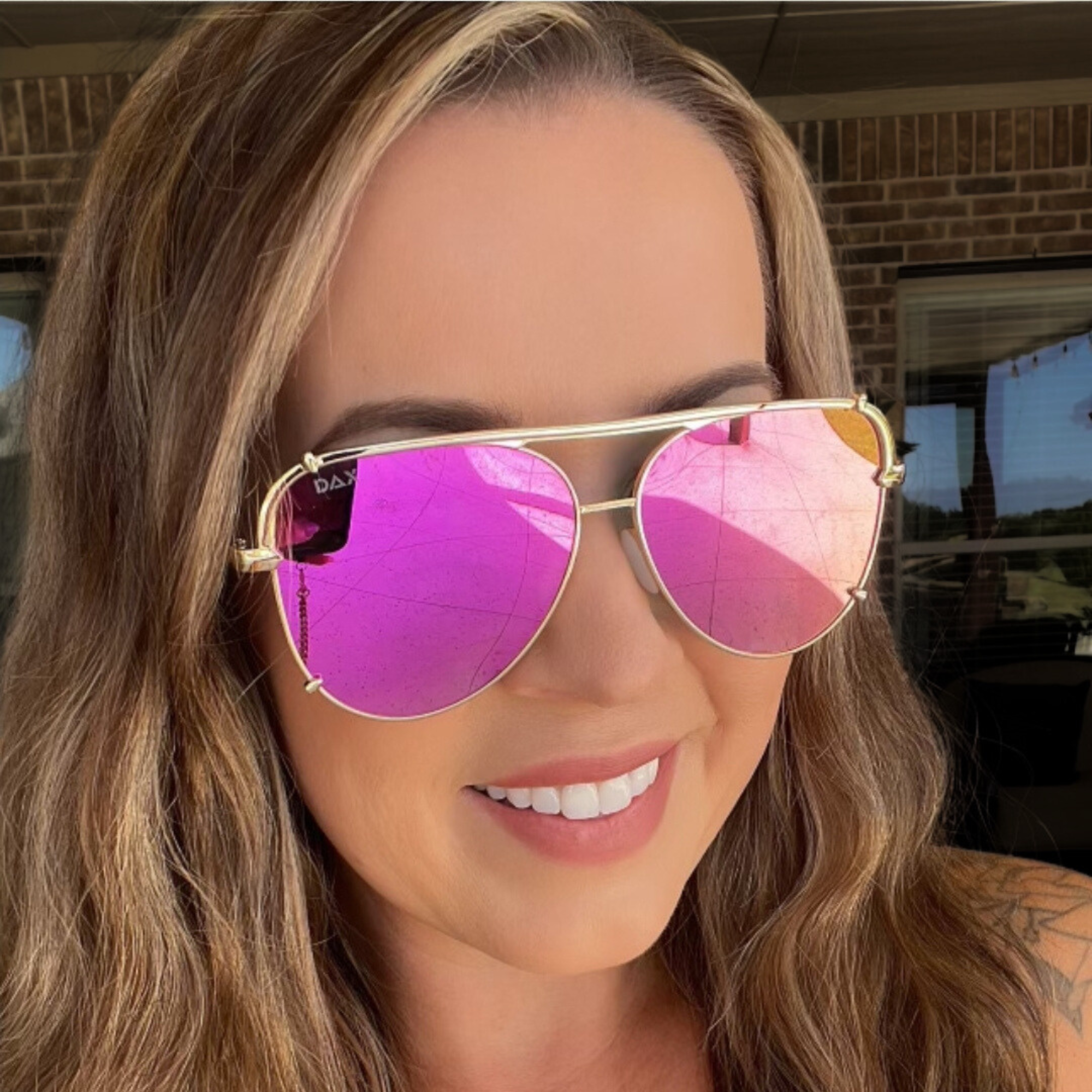 Woman wearing pink reflective sunglasses with a blurred background