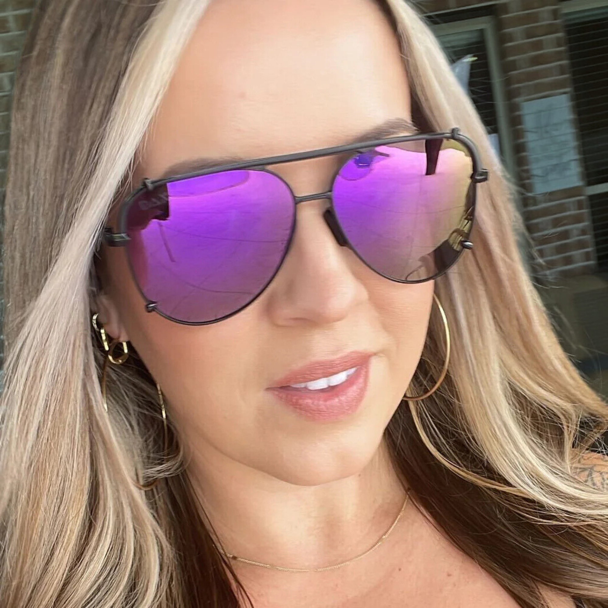 Woman wearing a pair of sunglasses with purple lenses.