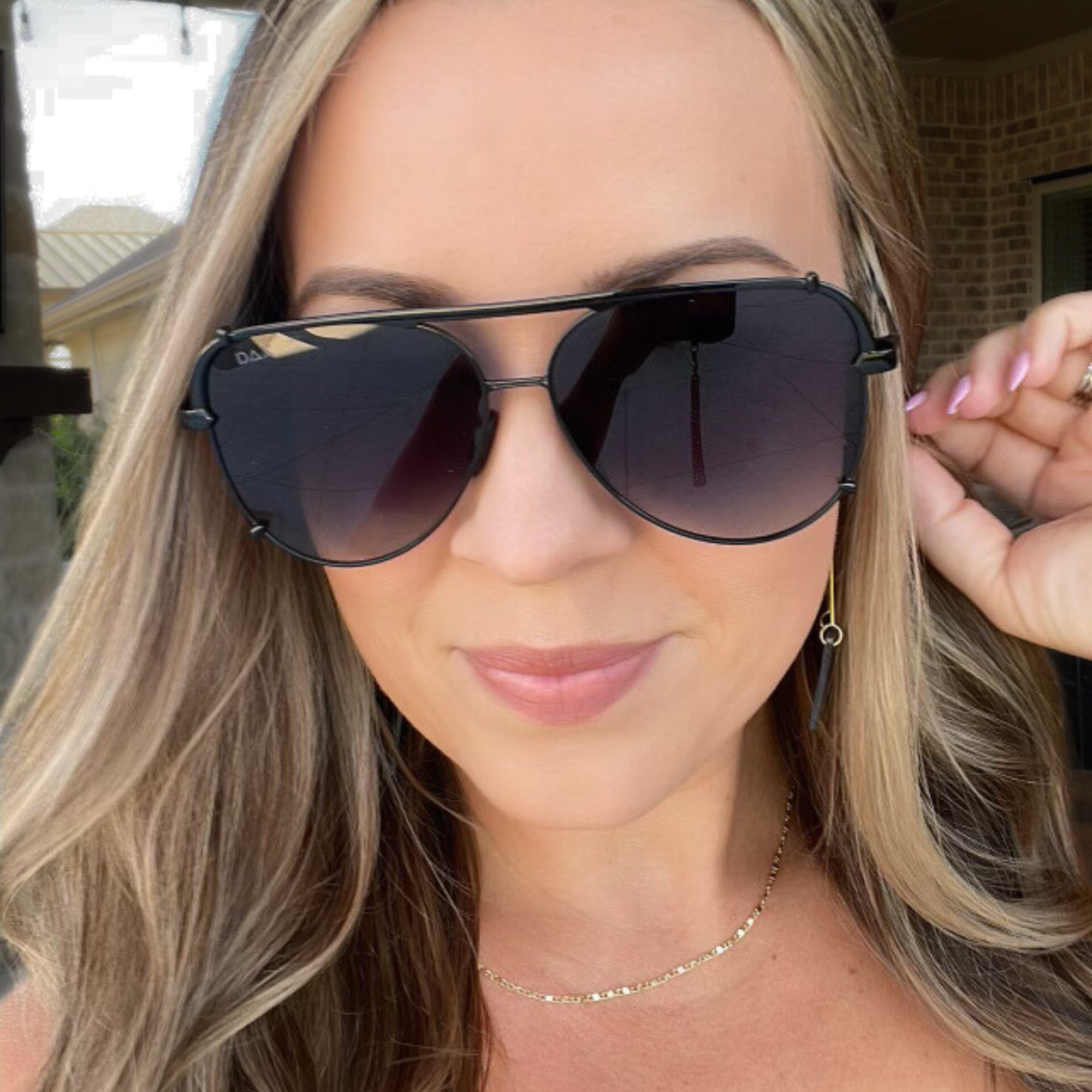 Woman wearing dark aviator sunglasses with a blurred background