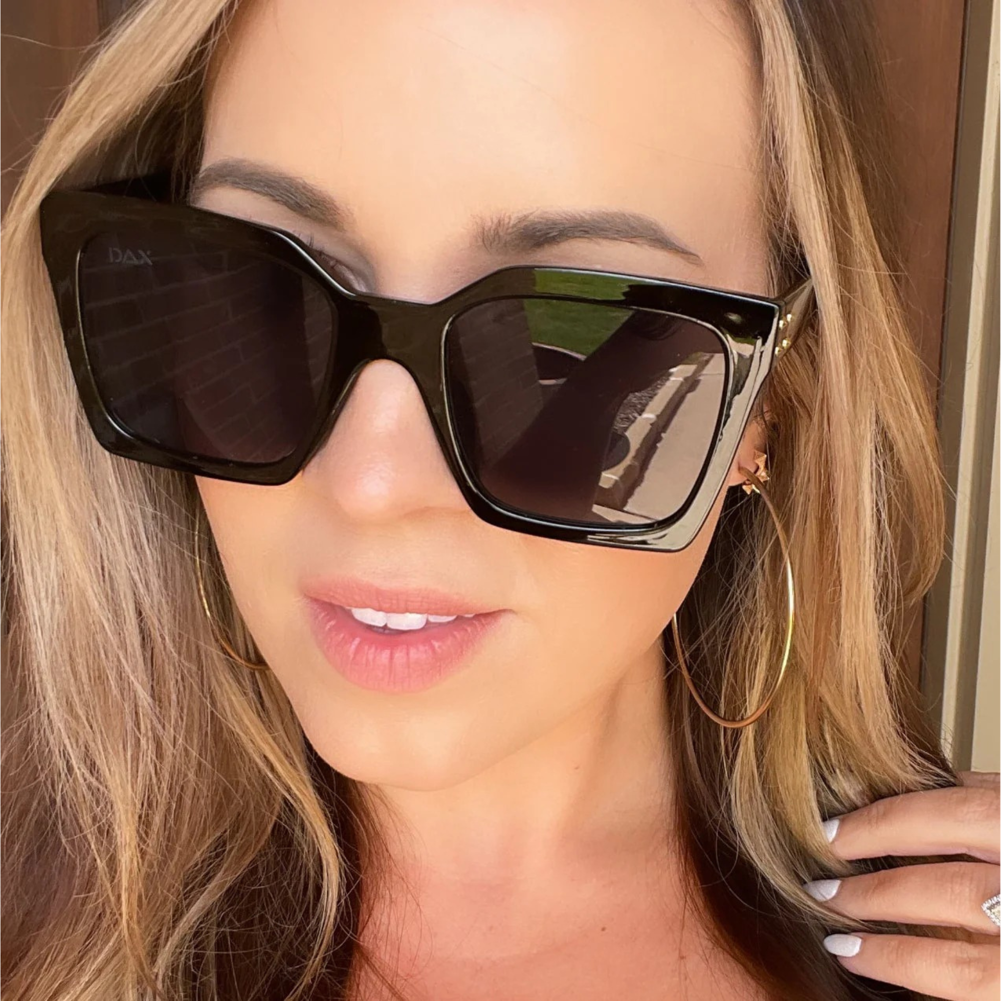 Woman wearing large black sunglasses with a neutral background
