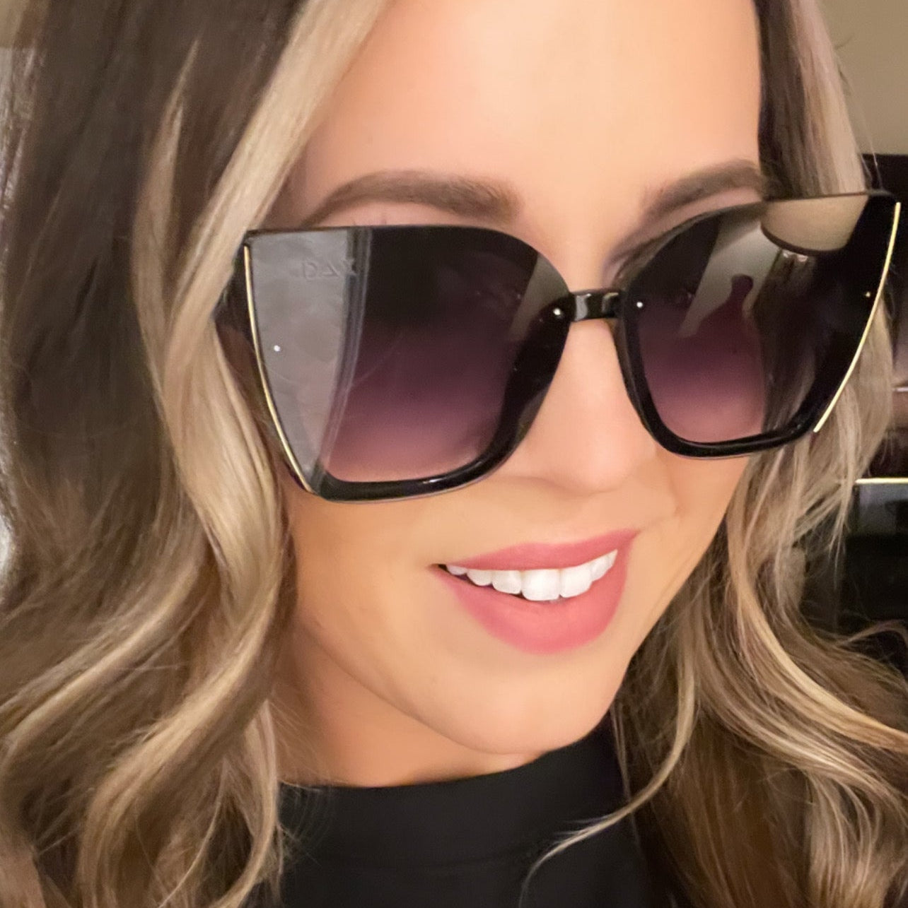 Woman wearing large black sunglasses with a blurred background