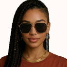 Woman wearing gold-framed sunglasses with a plain background