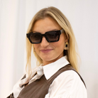 Woman wearing sunglasses and a vest against a white background