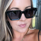 Close-up of a person wearing black sunglasses with 'DAX' branding.