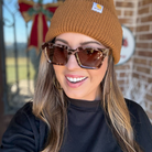 Woman wearing a brown beanie and sunglasses with a blurred background