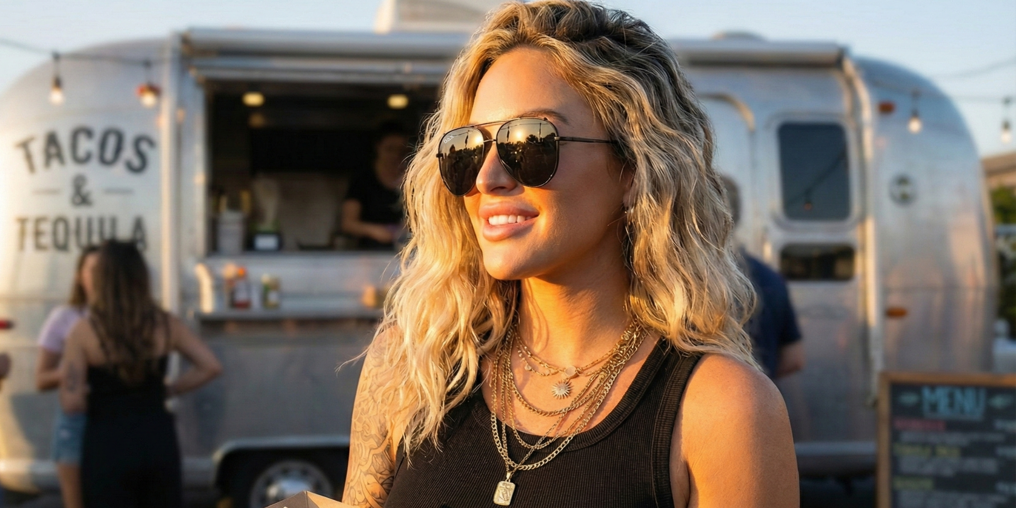 Woman wearing sunglasses in front of a food truck with 'Tacos & Tequila' text.