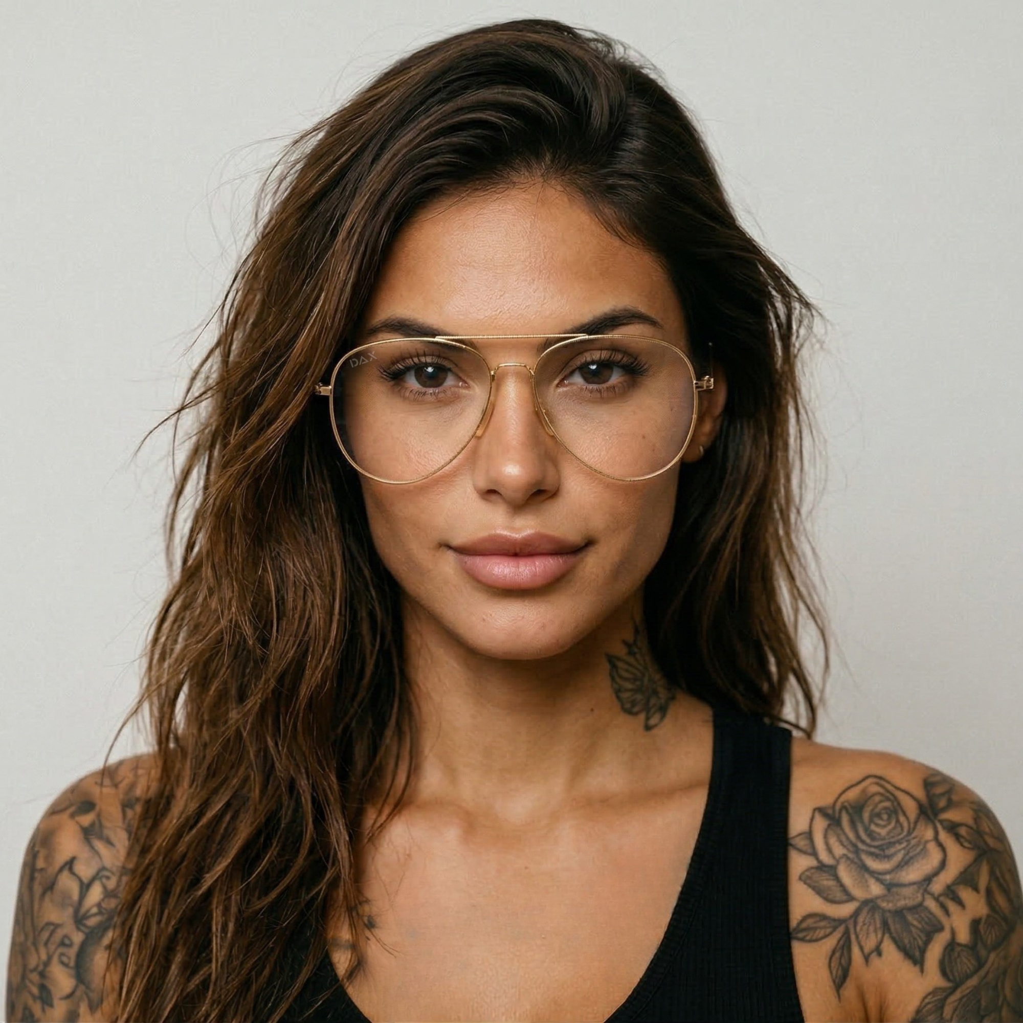 Woman with tattoos wearing glasses against a plain background