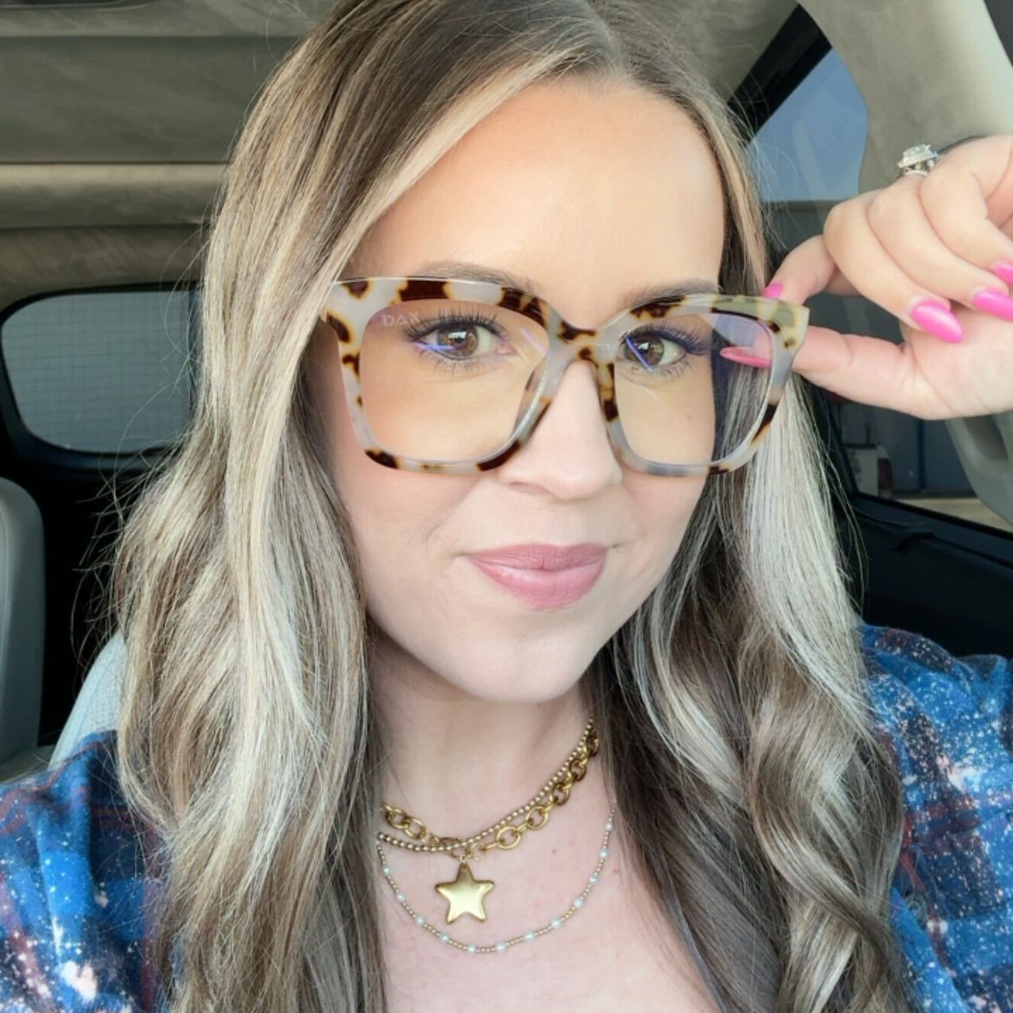 Woman wearing tortoiseshell glasses inside a vehicle