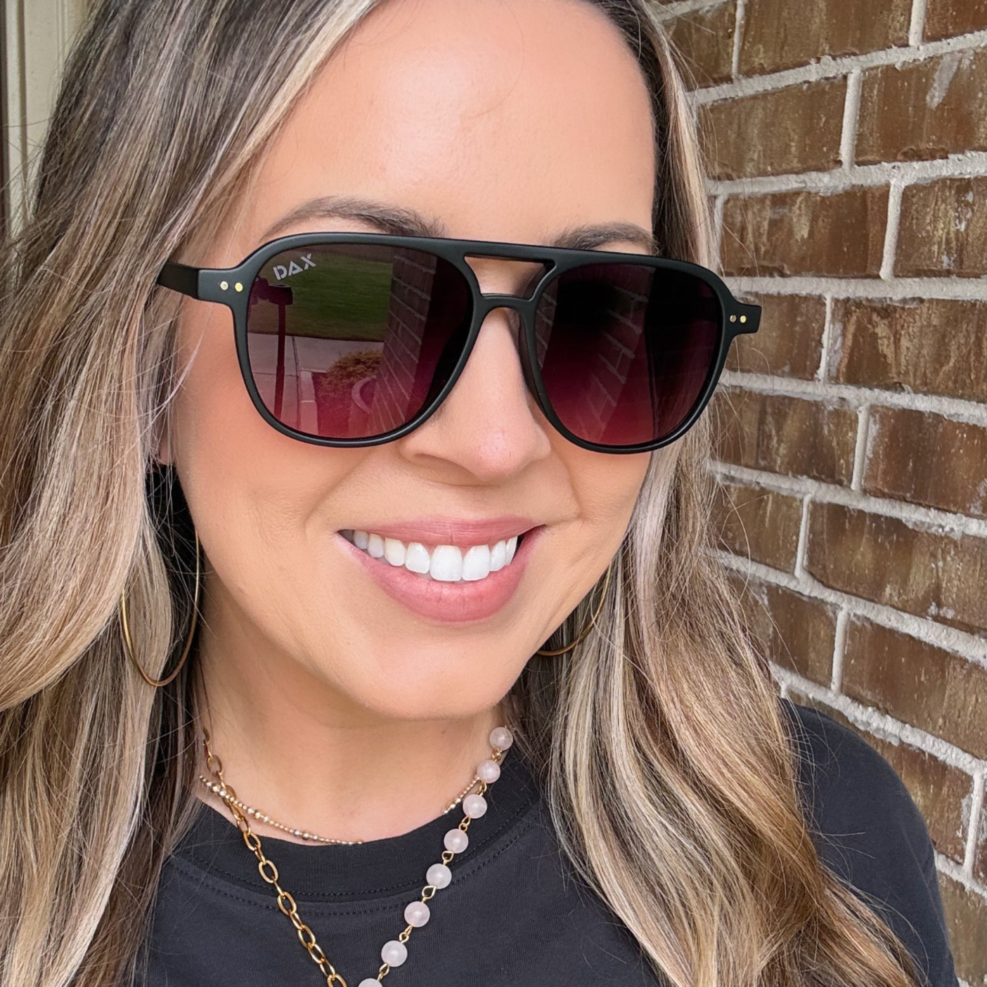 Woman wearing black sunglasses with a brick wall background