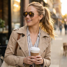 Woman in a beige coat holding a coffee cup on a city street
