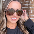 Woman wearing sunglasses with a brick wall background